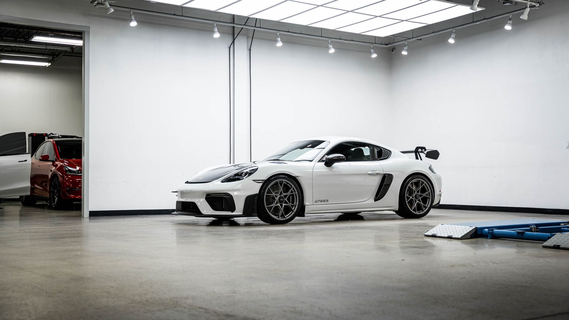 A white sports car is parked in a garage.