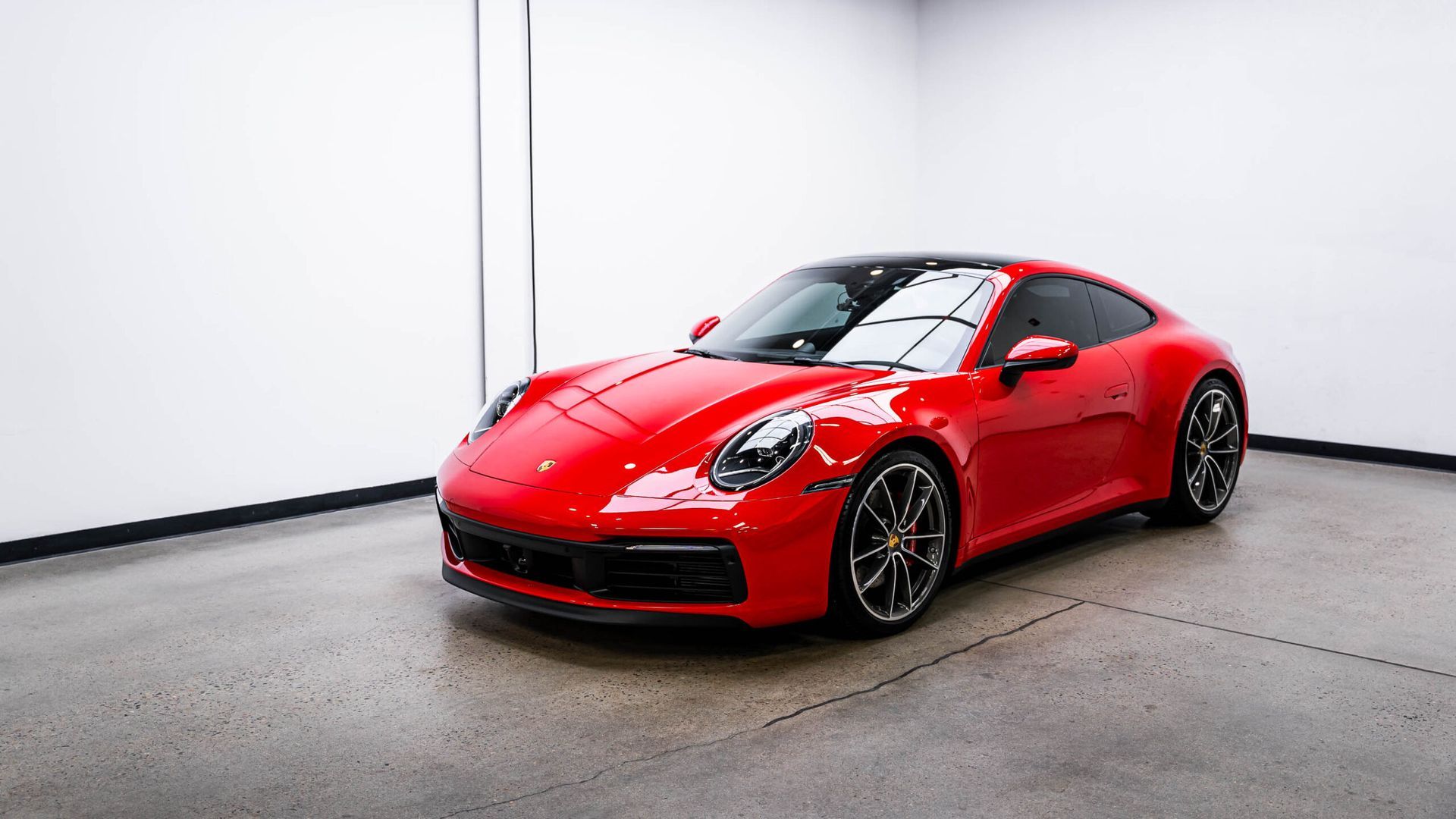 A red porsche 911 is parked in a garage.