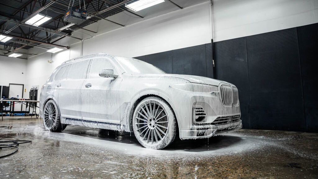 A car is covered in foam in a garage.