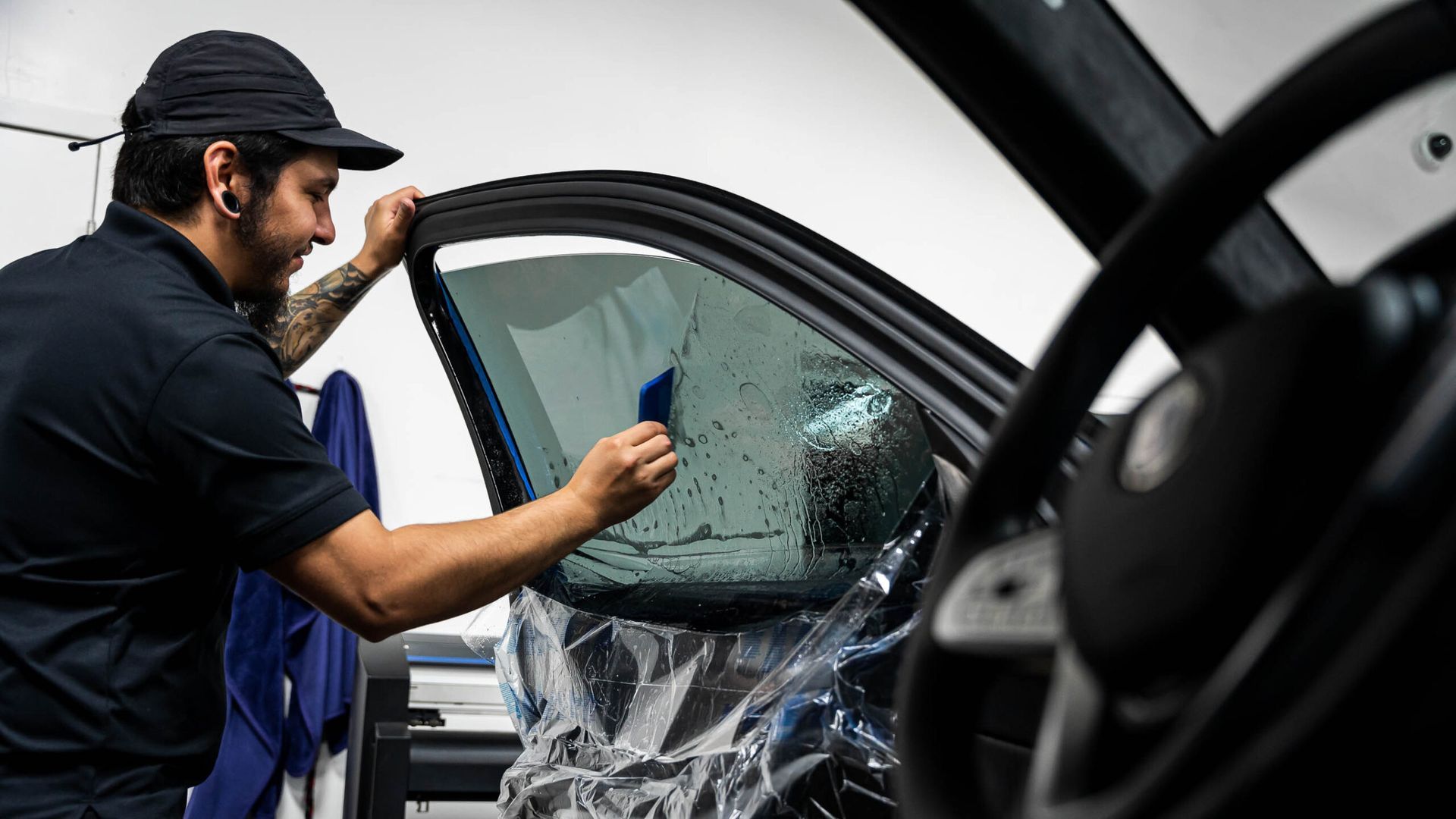 A man is applying tinted glass to a car window.