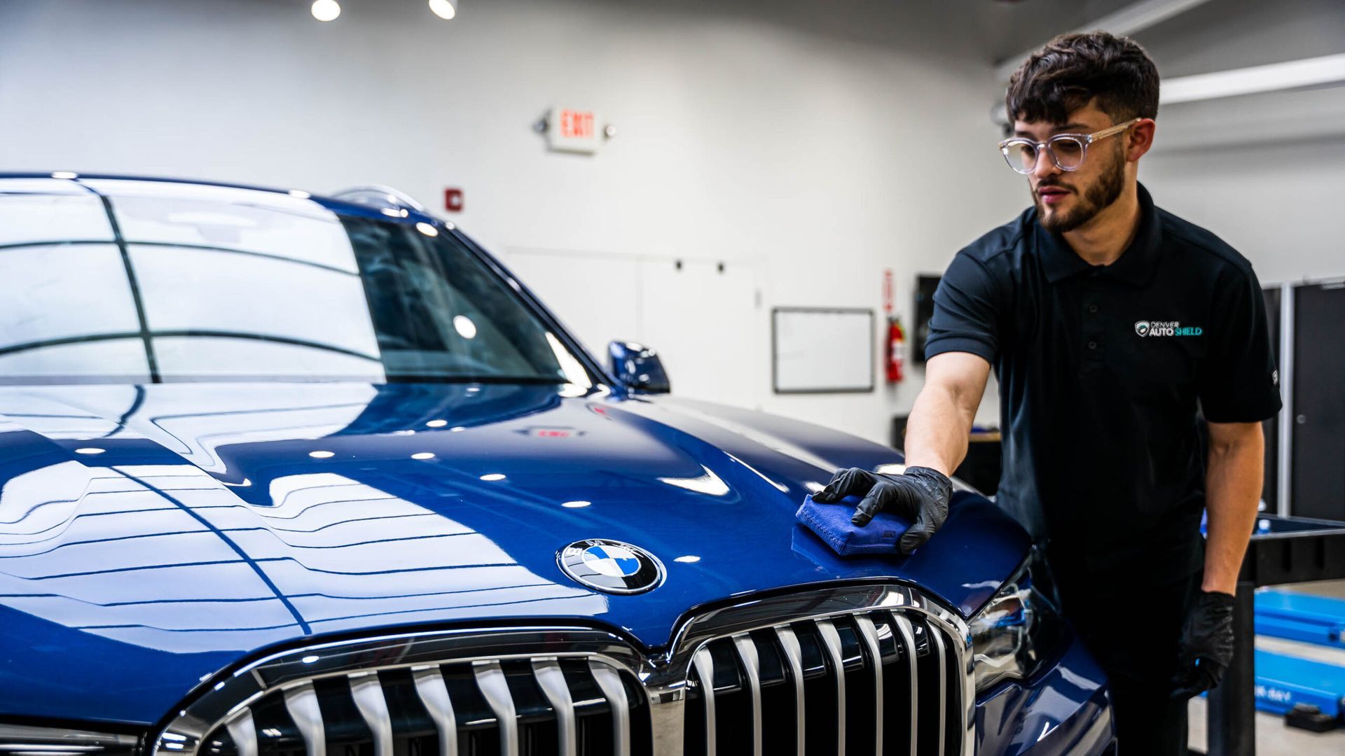 A man is polishing a blue car in a garage.