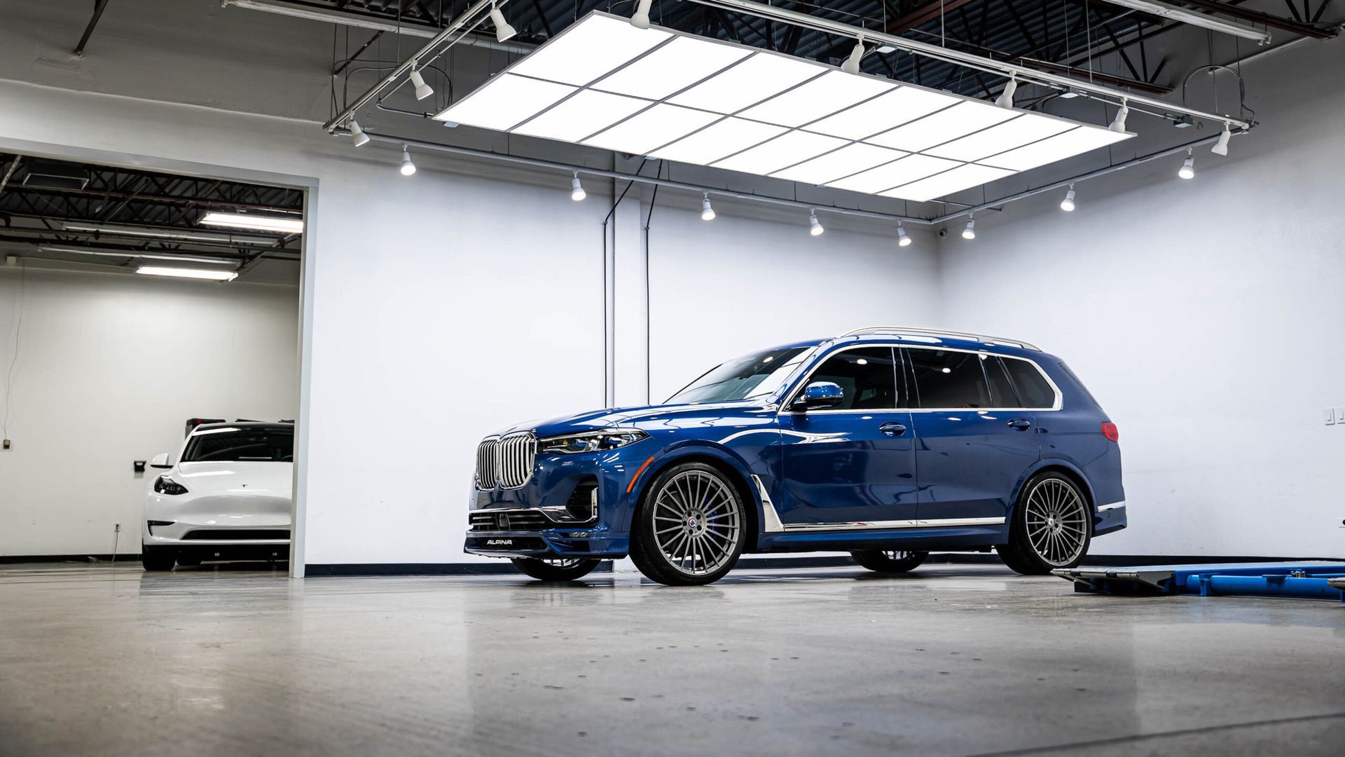 A blue bmw x7 is parked in a garage.