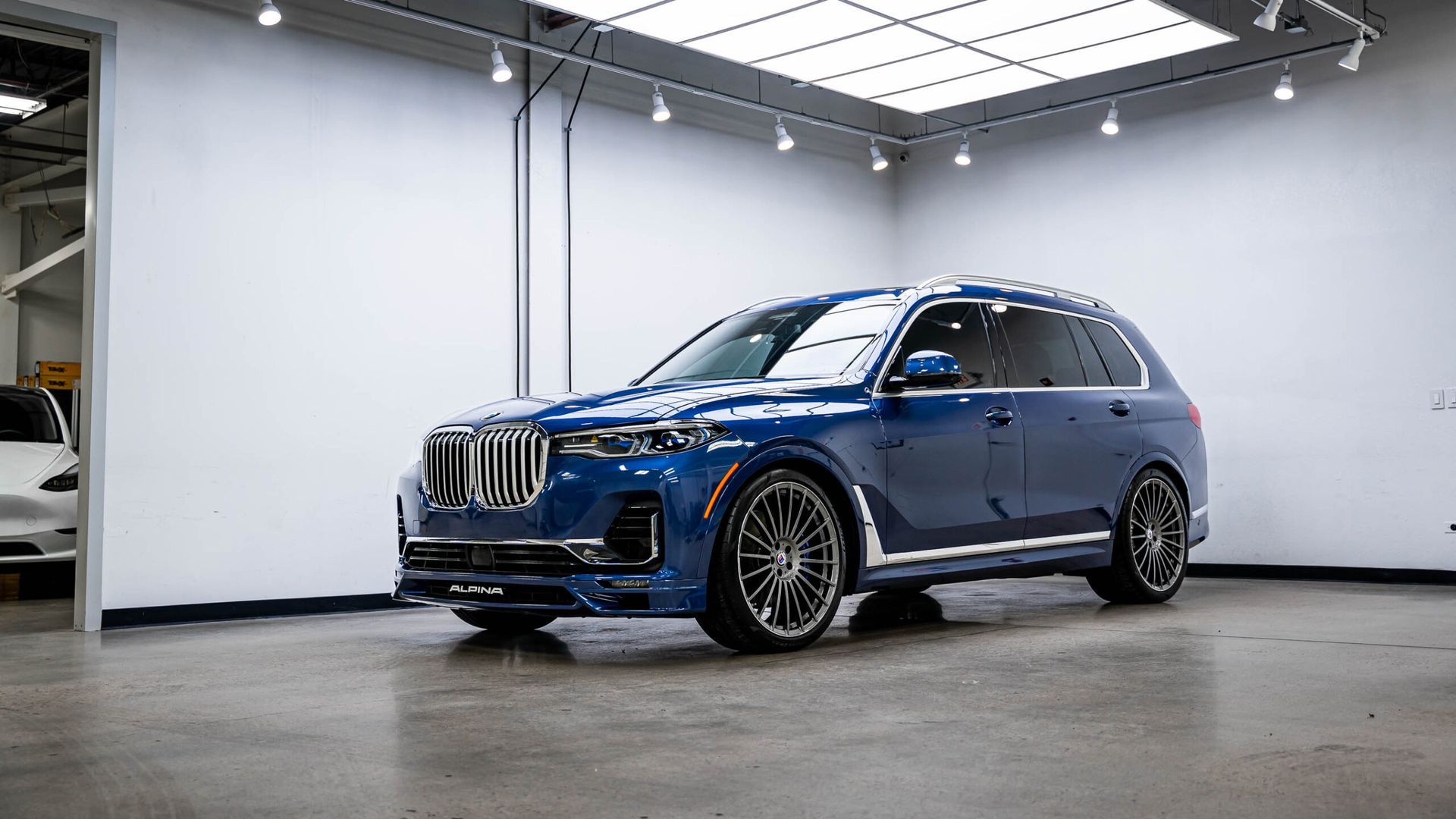 A blue bmw x7 is parked in a garage.