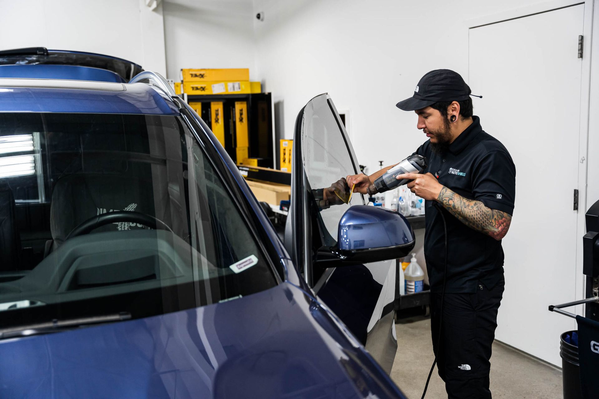 A man is working on a blue car in a garage.