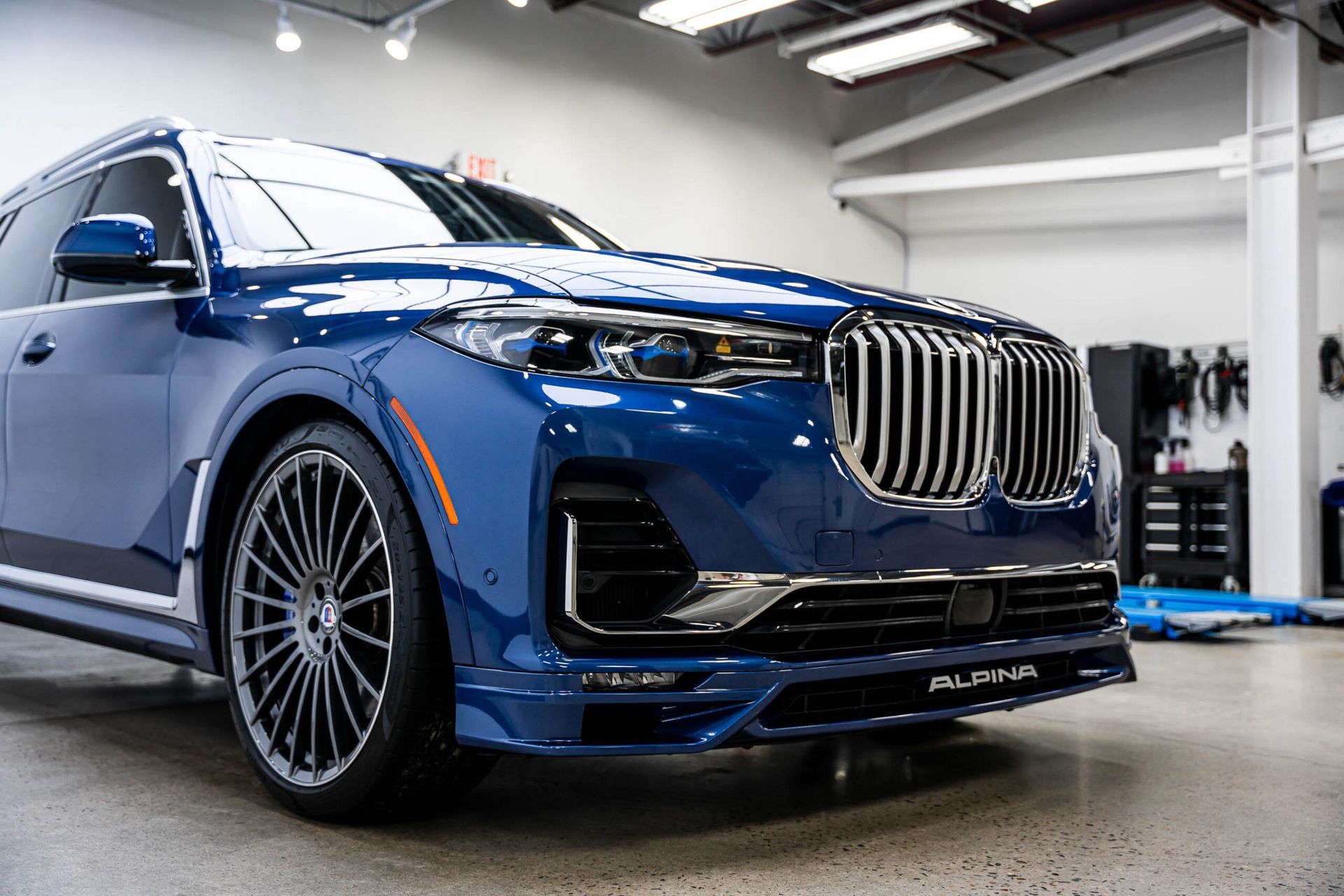 A blue bmw x7 is parked in a garage.