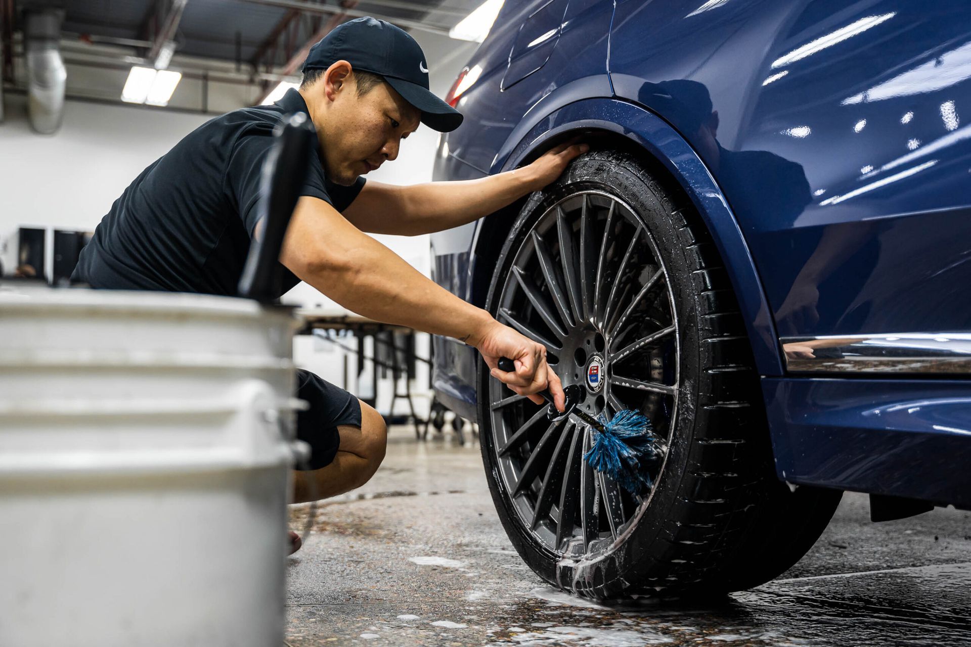 A man is cleaning a car wheel with a brush.