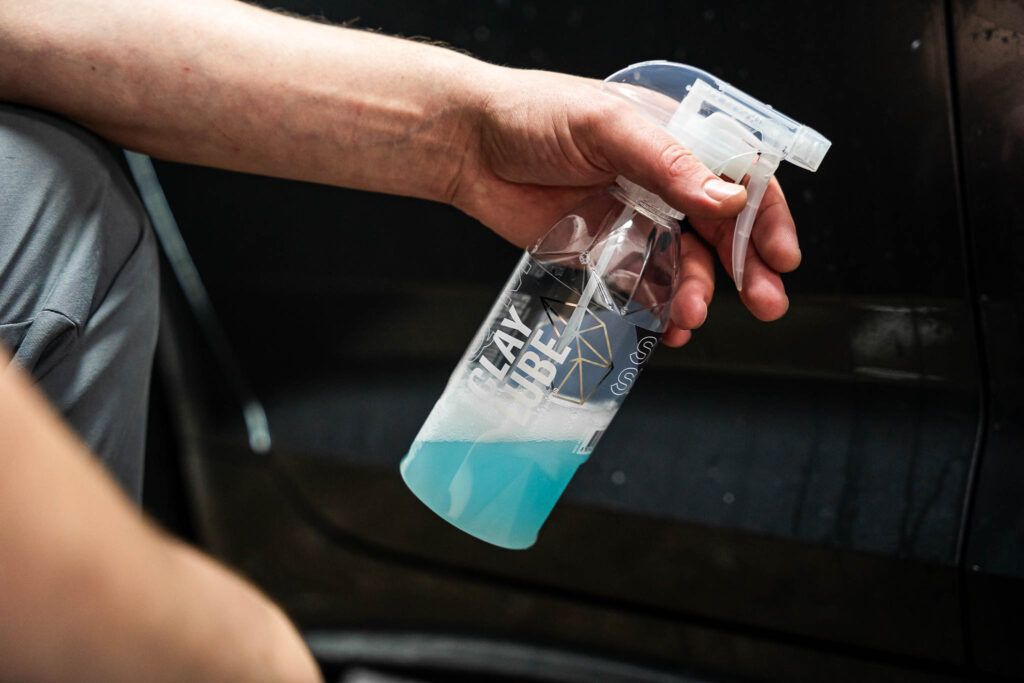 A person is holding a spray bottle with blue liquid in it.