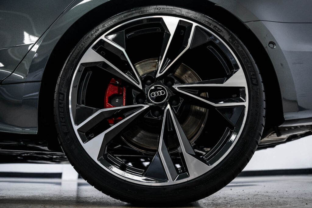 A close up of a car wheel with a red brake caliper.