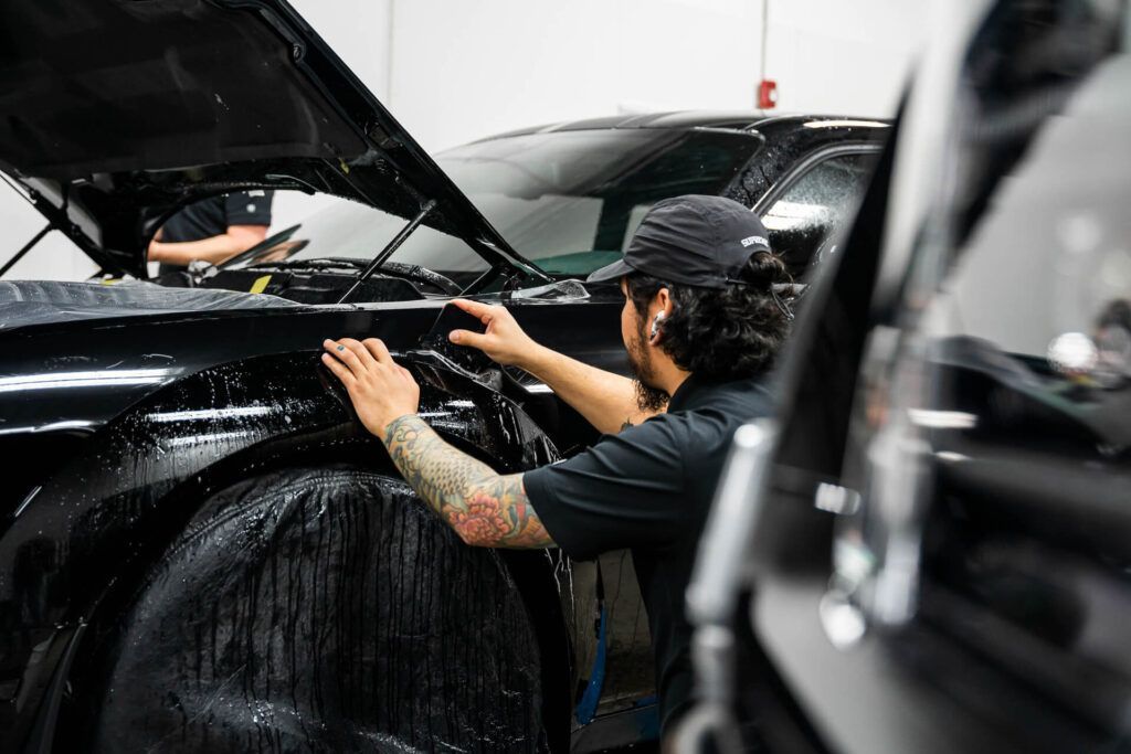 A man is working on a black car in a garage.