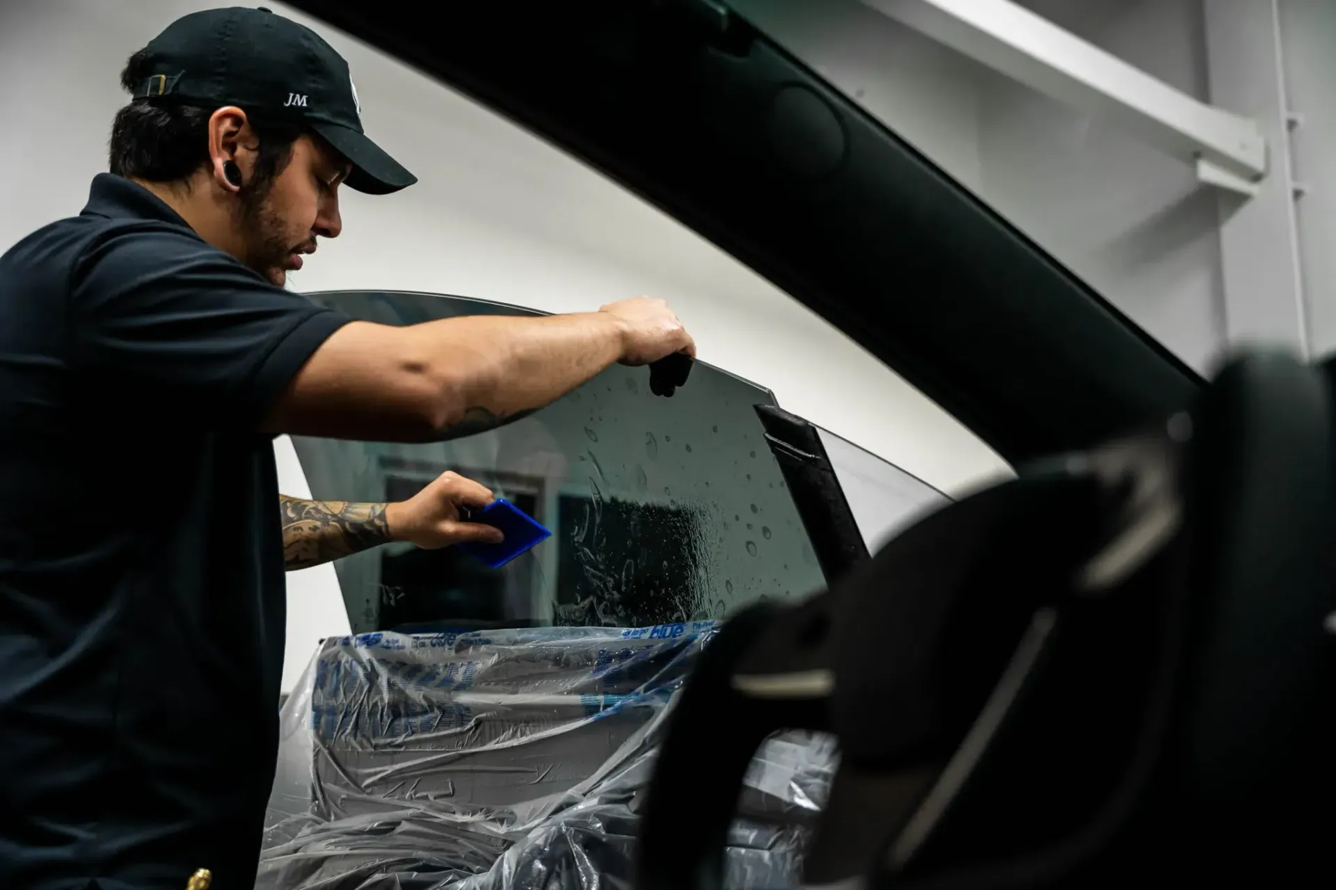 A man is applying window tinting to a car window.