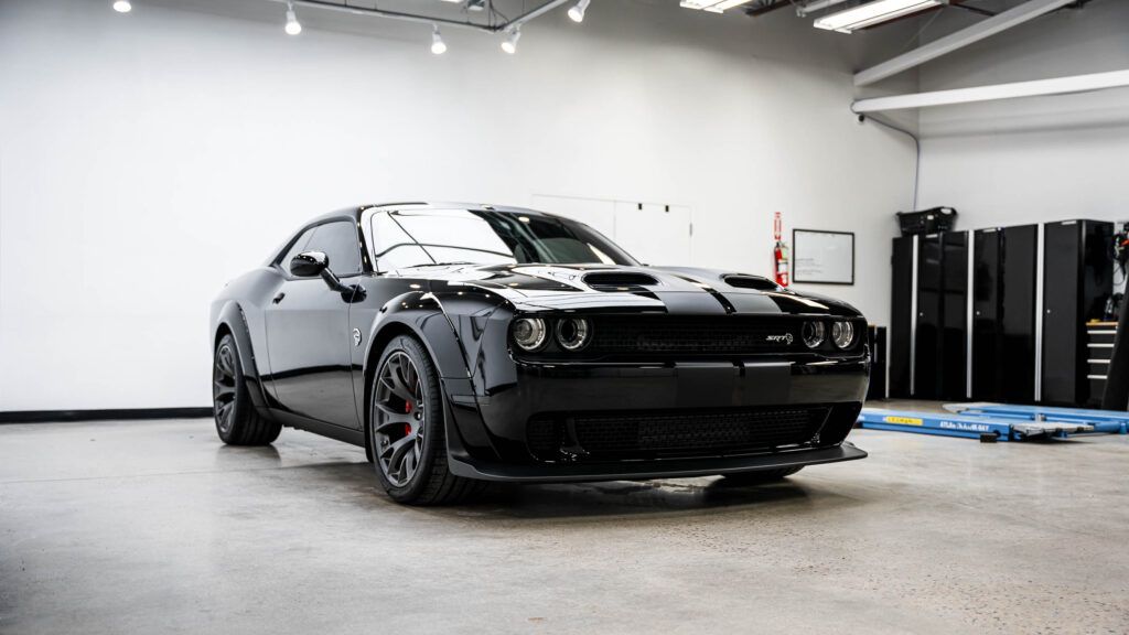 A black dodge challenger is parked in a garage.