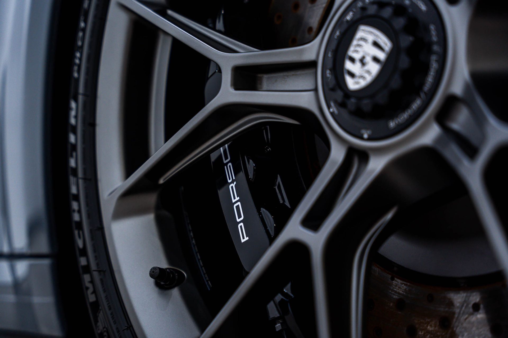 A close up of a porsche wheel with a brake caliper on it.