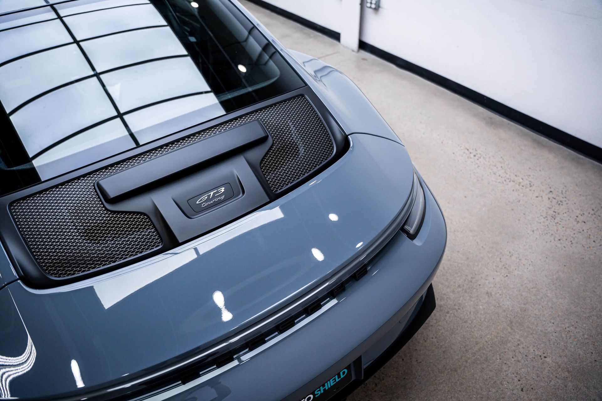 The rear end of a gray porsche 911 is shown in a garage.