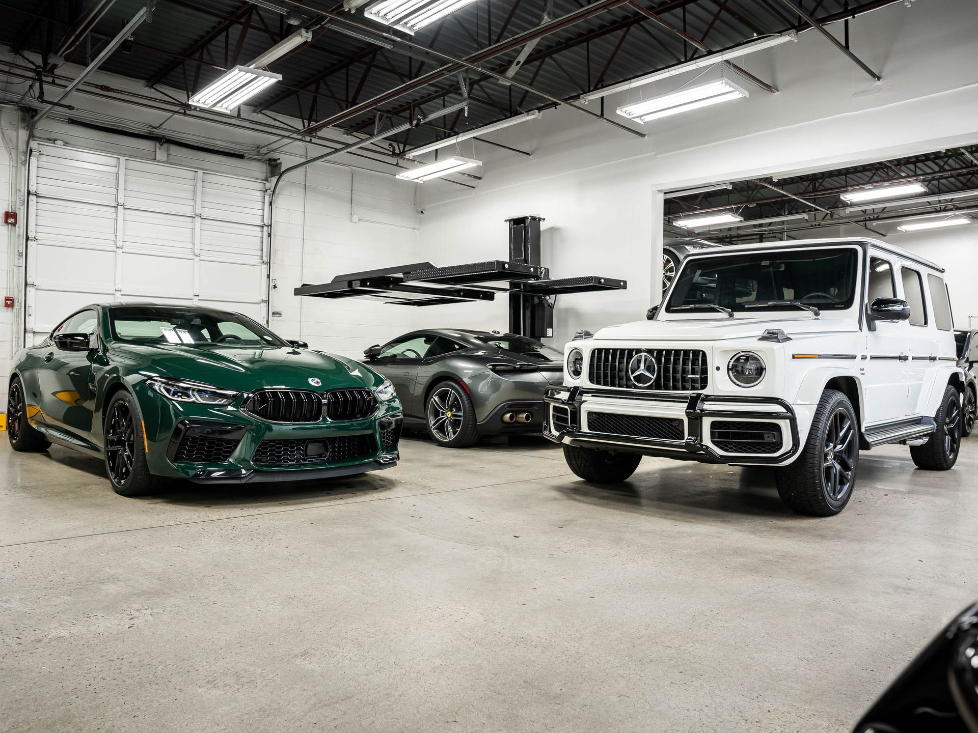 Two cars are parked in a garage next to each other.