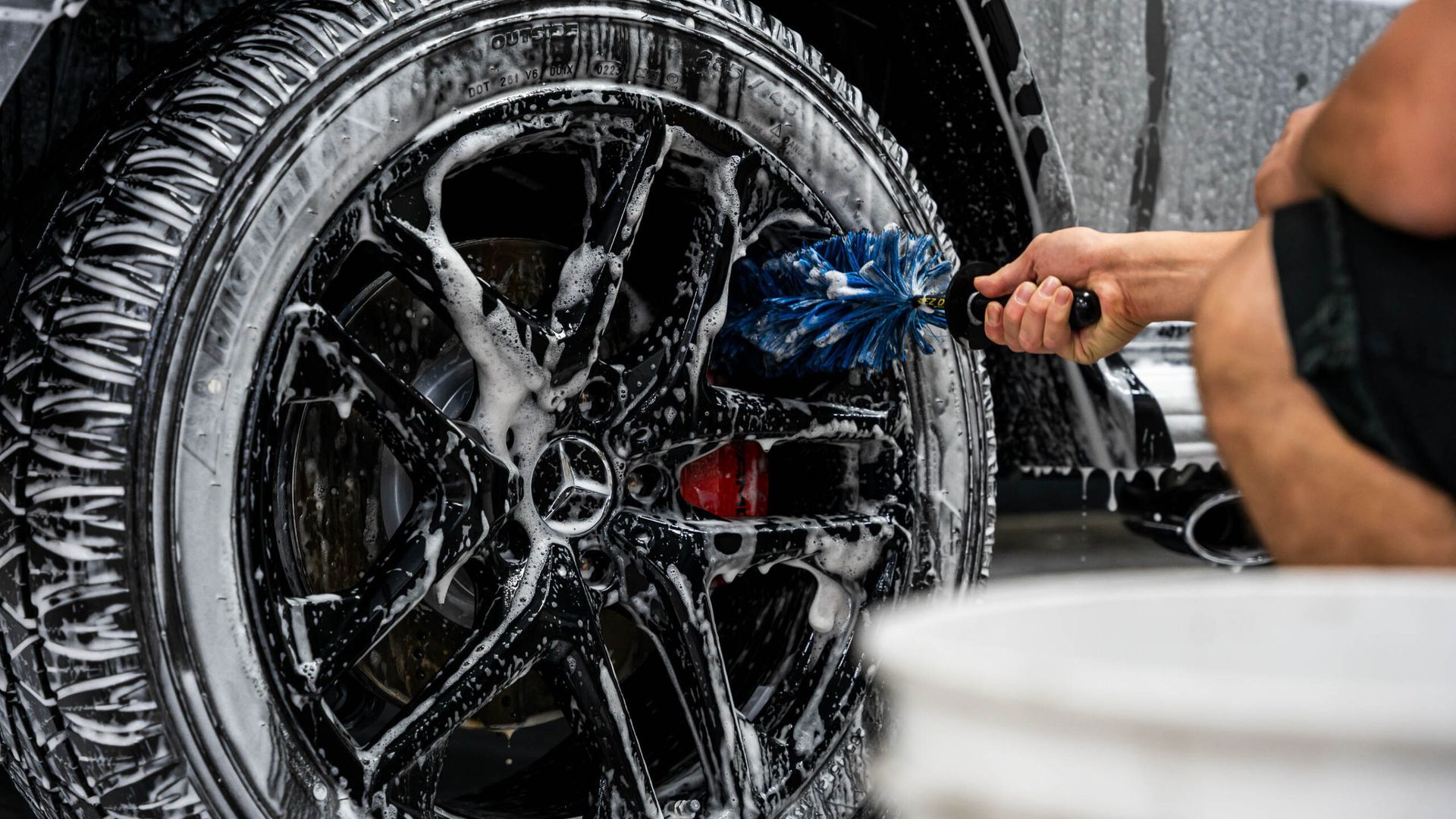 A man is washing a car wheel with a brush.