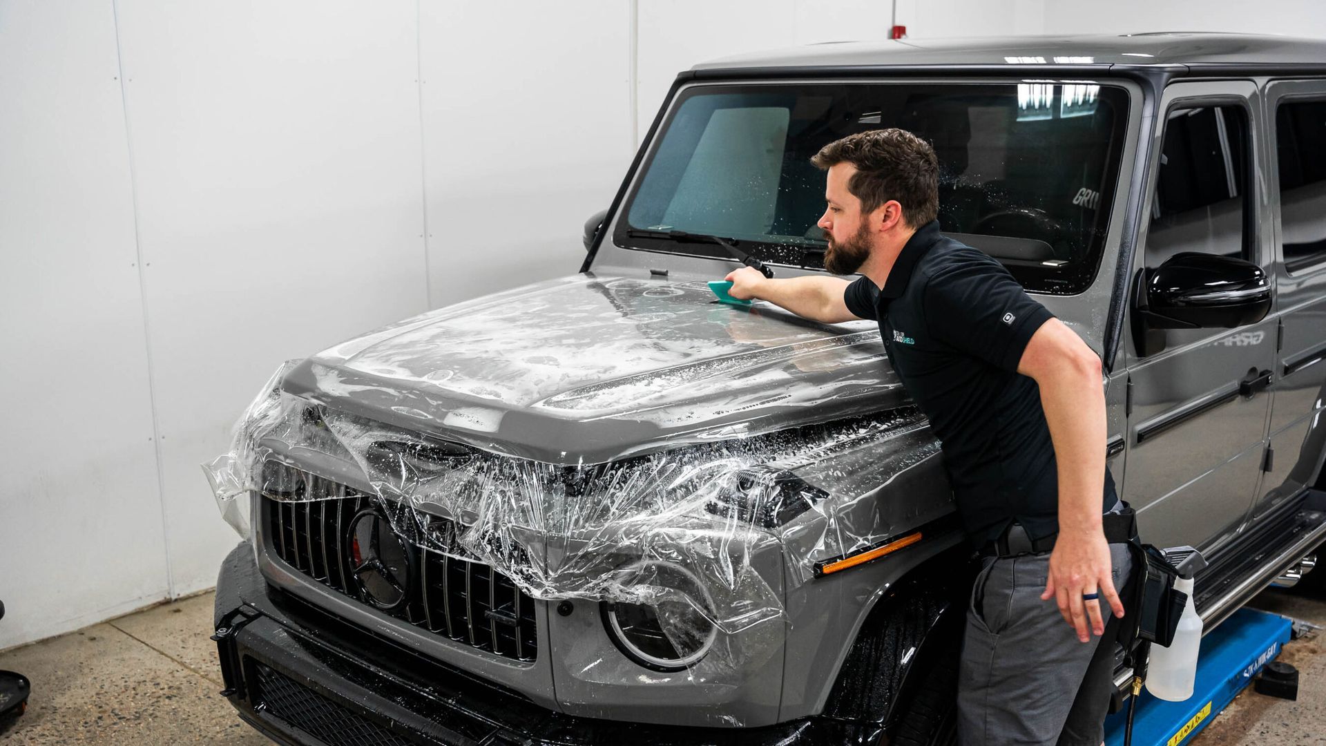 A man is wrapping a jeep with plastic wrap.