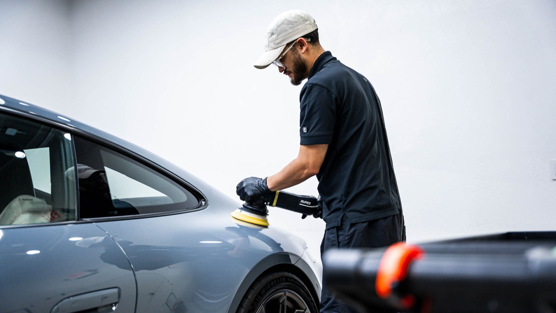 A man is polishing a car with a machine.