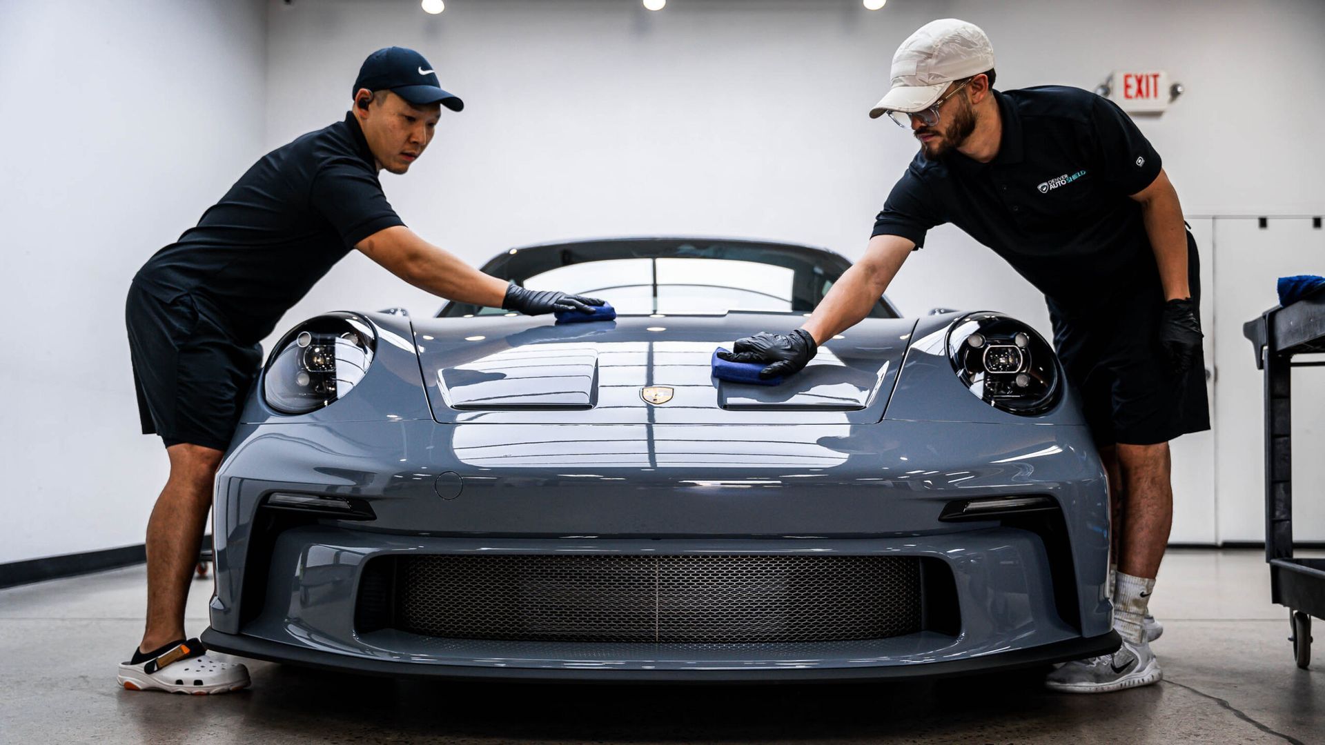 Two men are cleaning a car in a garage.