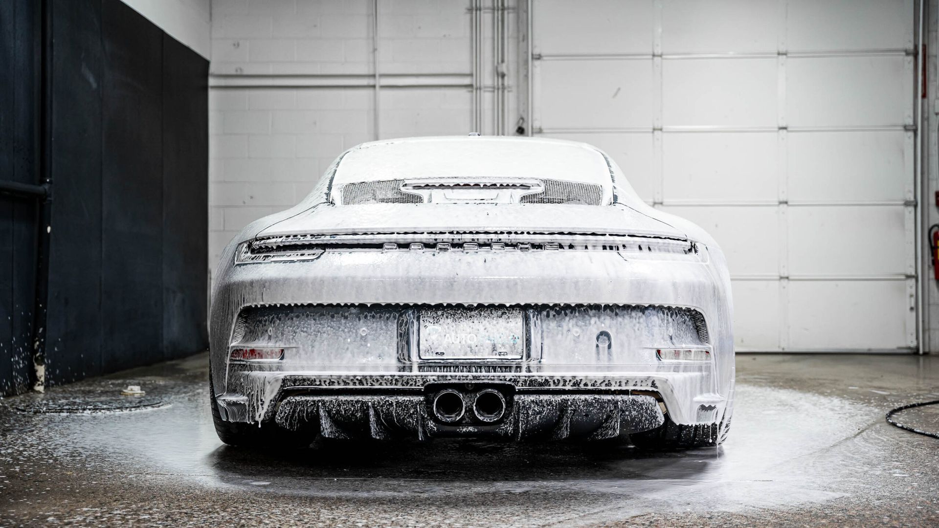 A car is covered in foam in a garage.