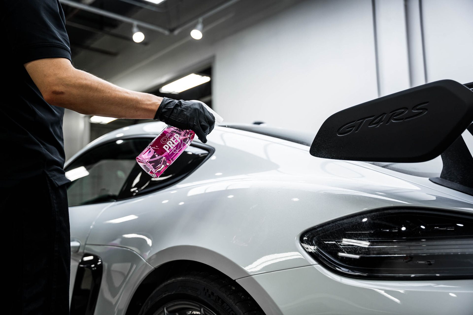 A man is spraying a car with a spray bottle.