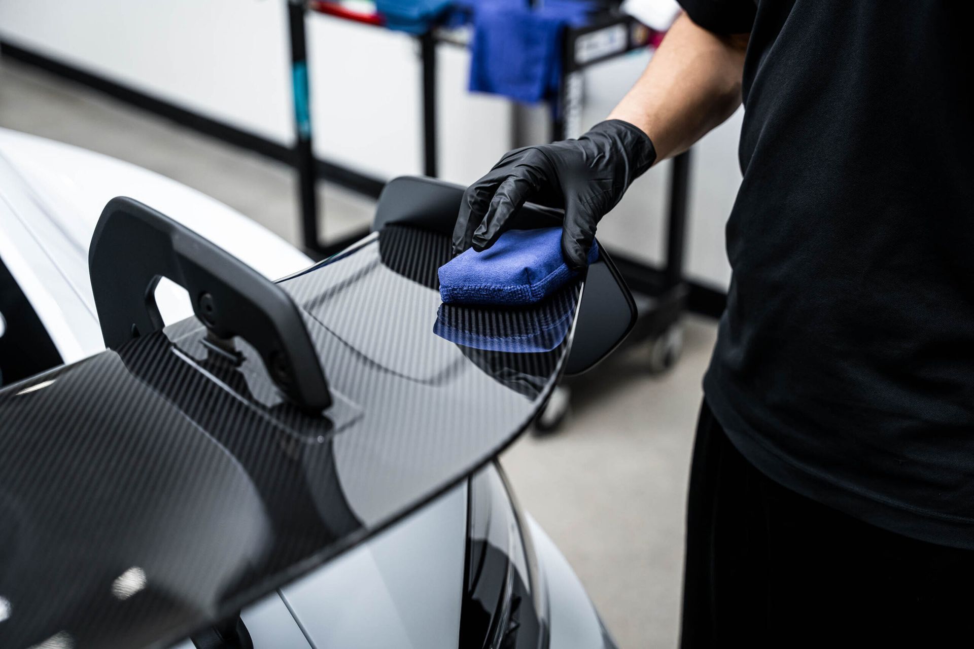 A person is cleaning the spoiler of a car with a cloth.