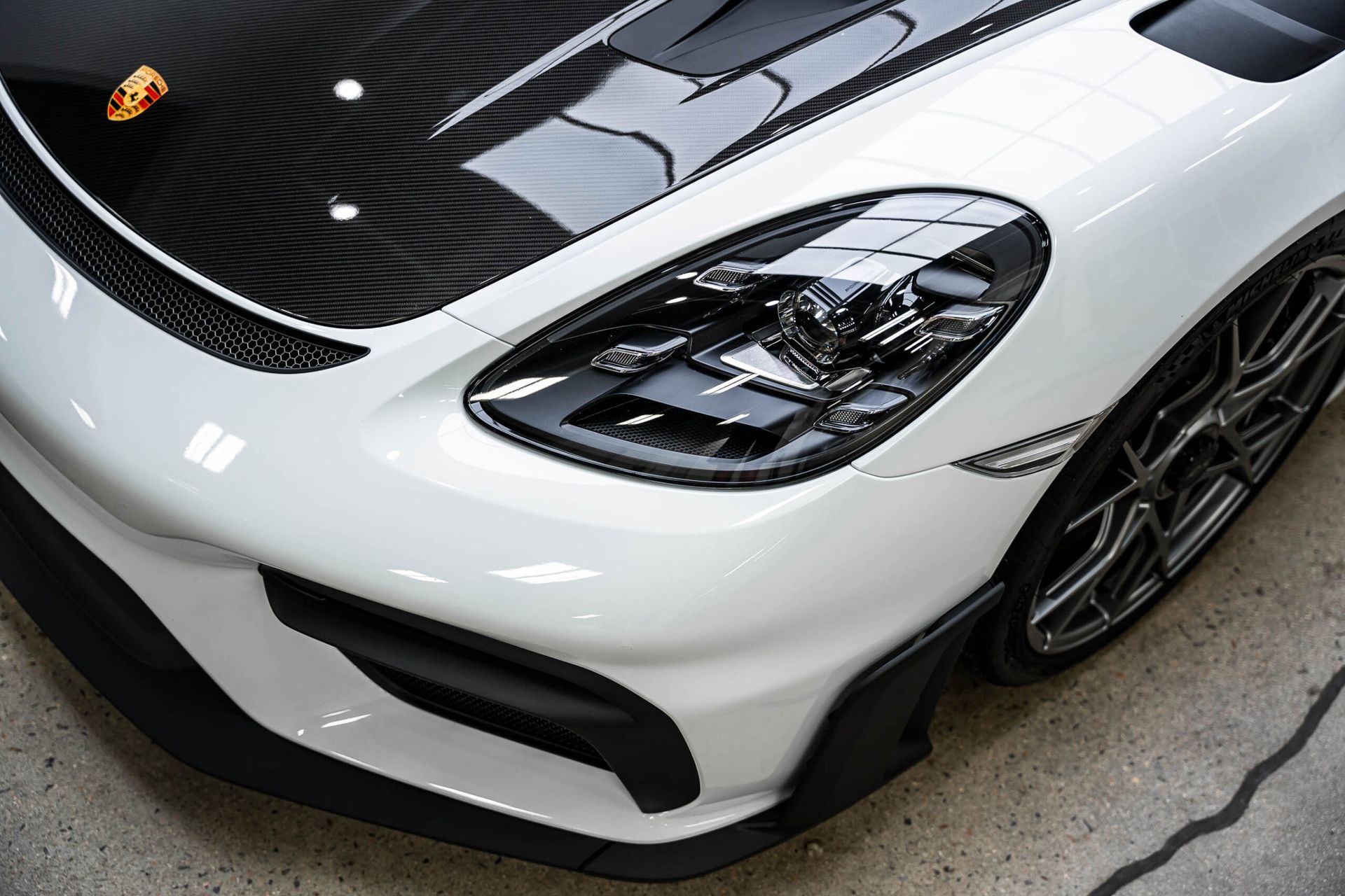 A close up of a white car with a black hood and headlights.