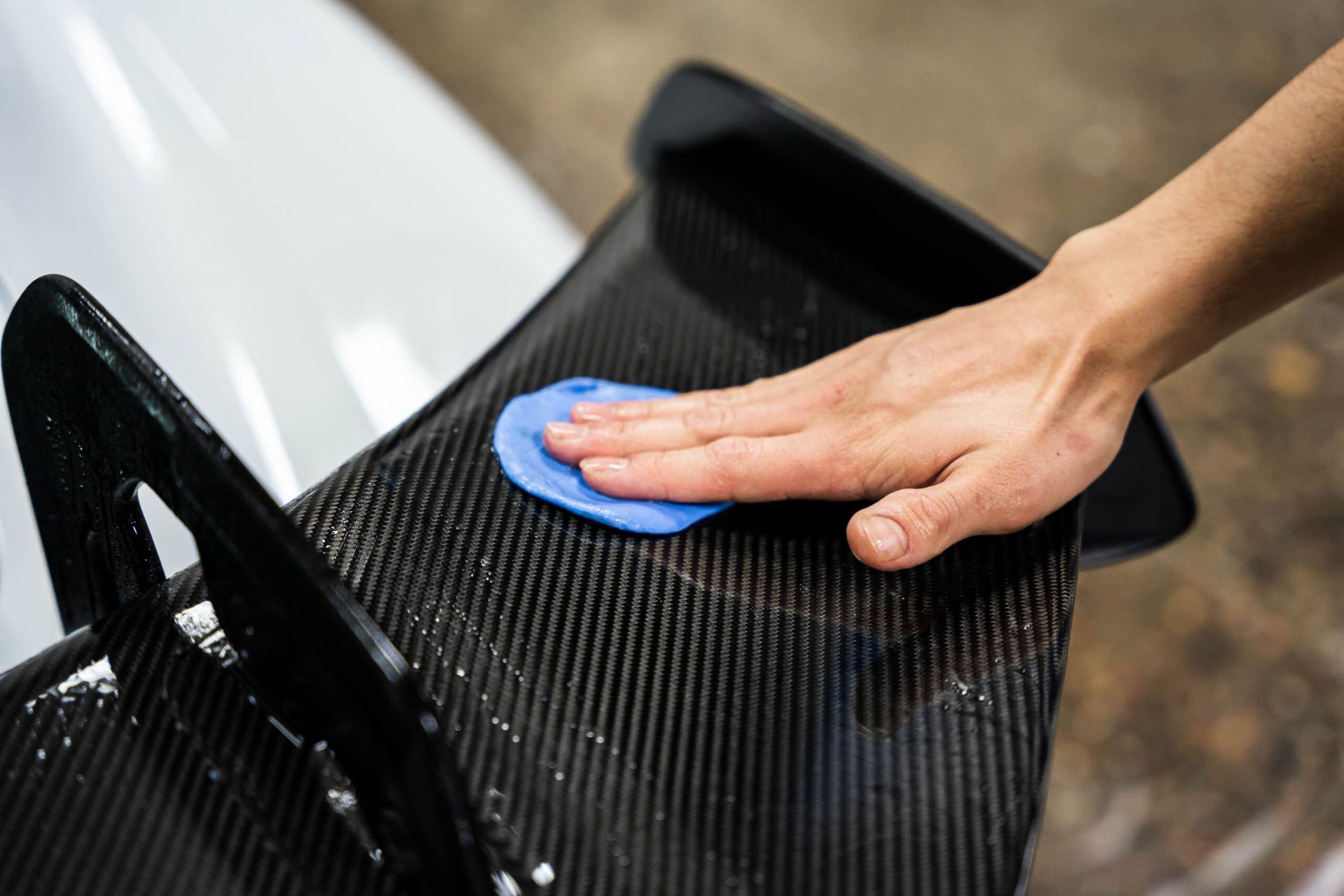 A person is applying wax to a car wing.