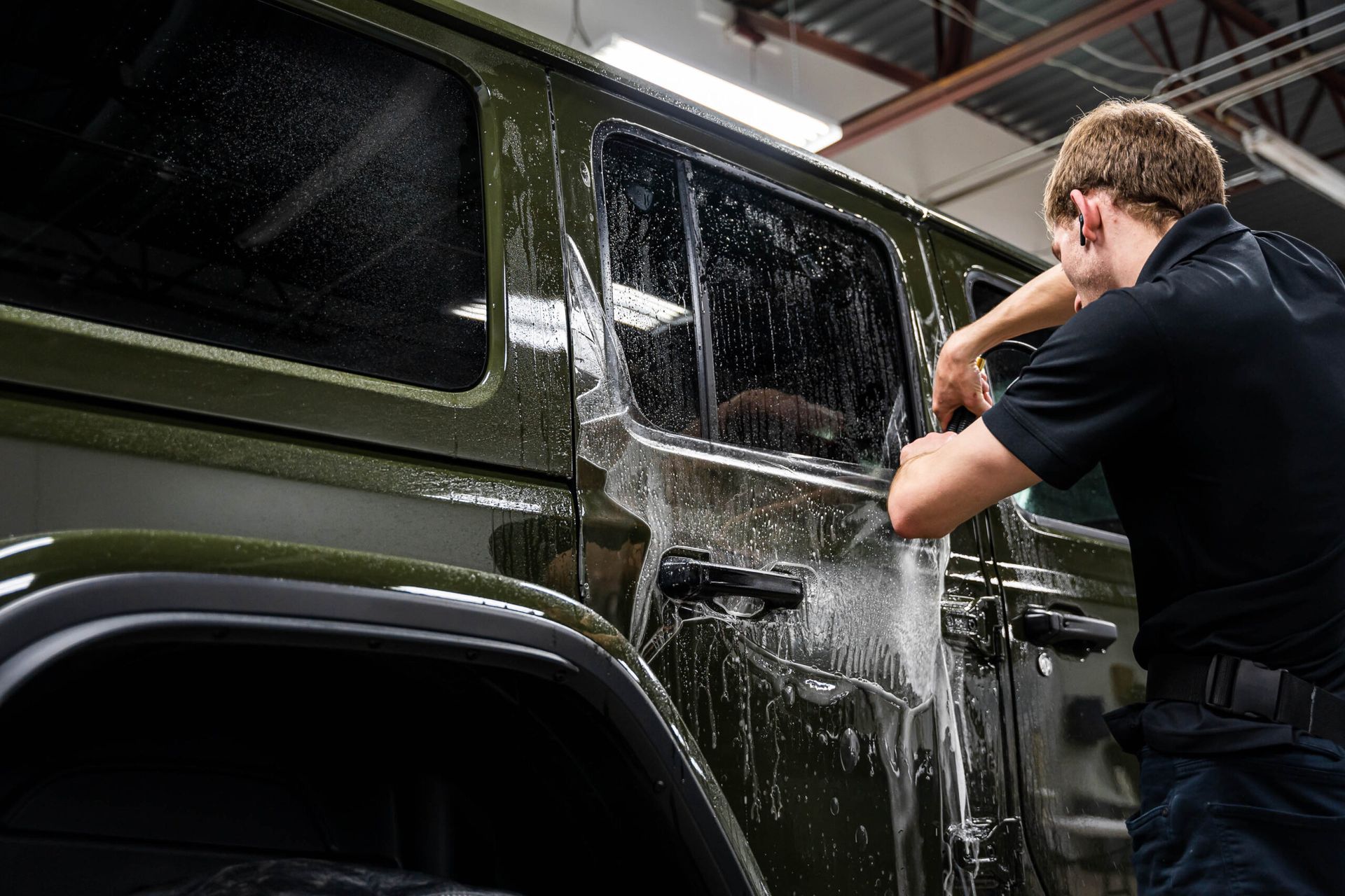 A man is washing a jeep in a garage.