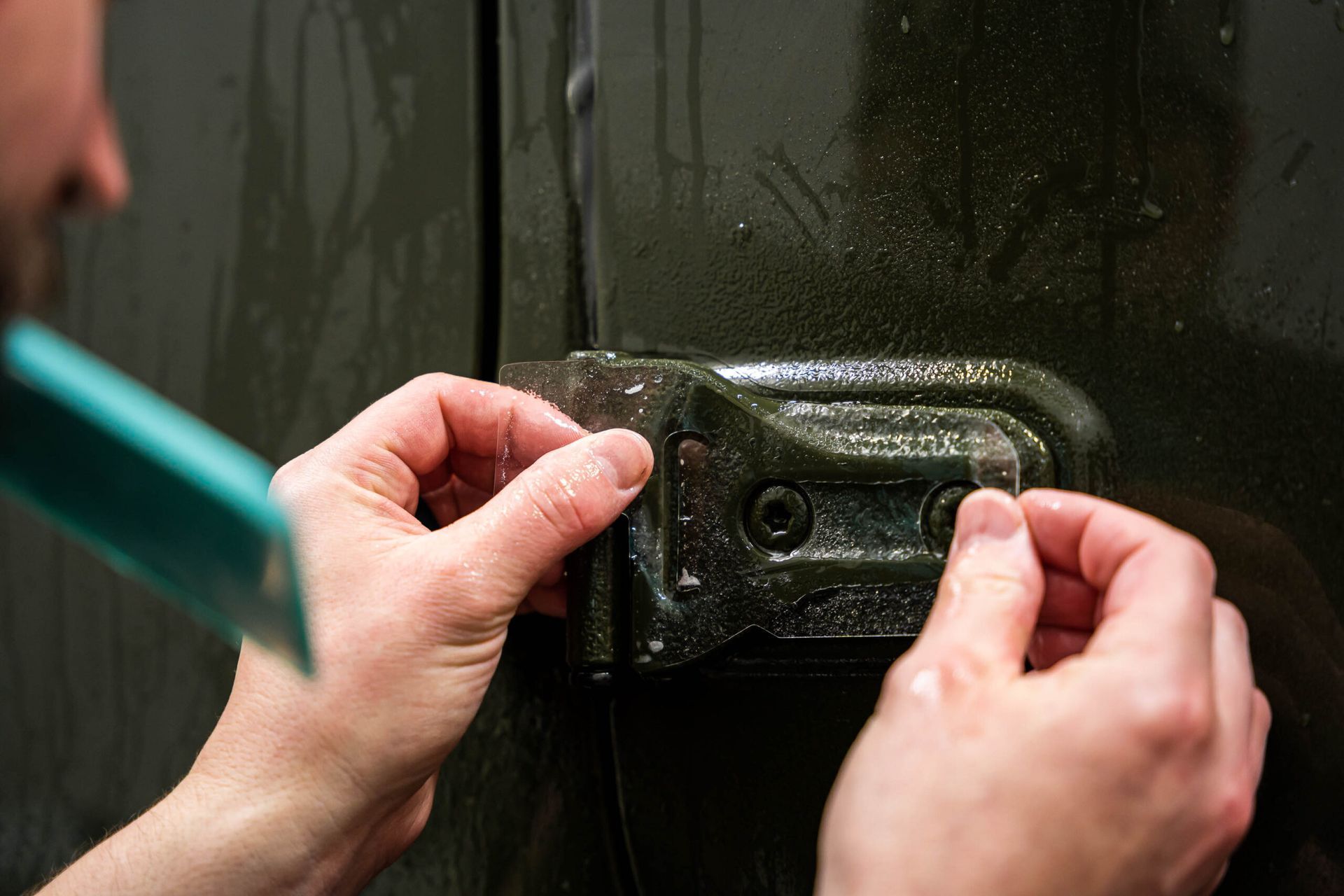 A person is peeling off a piece of plastic from a door handle.