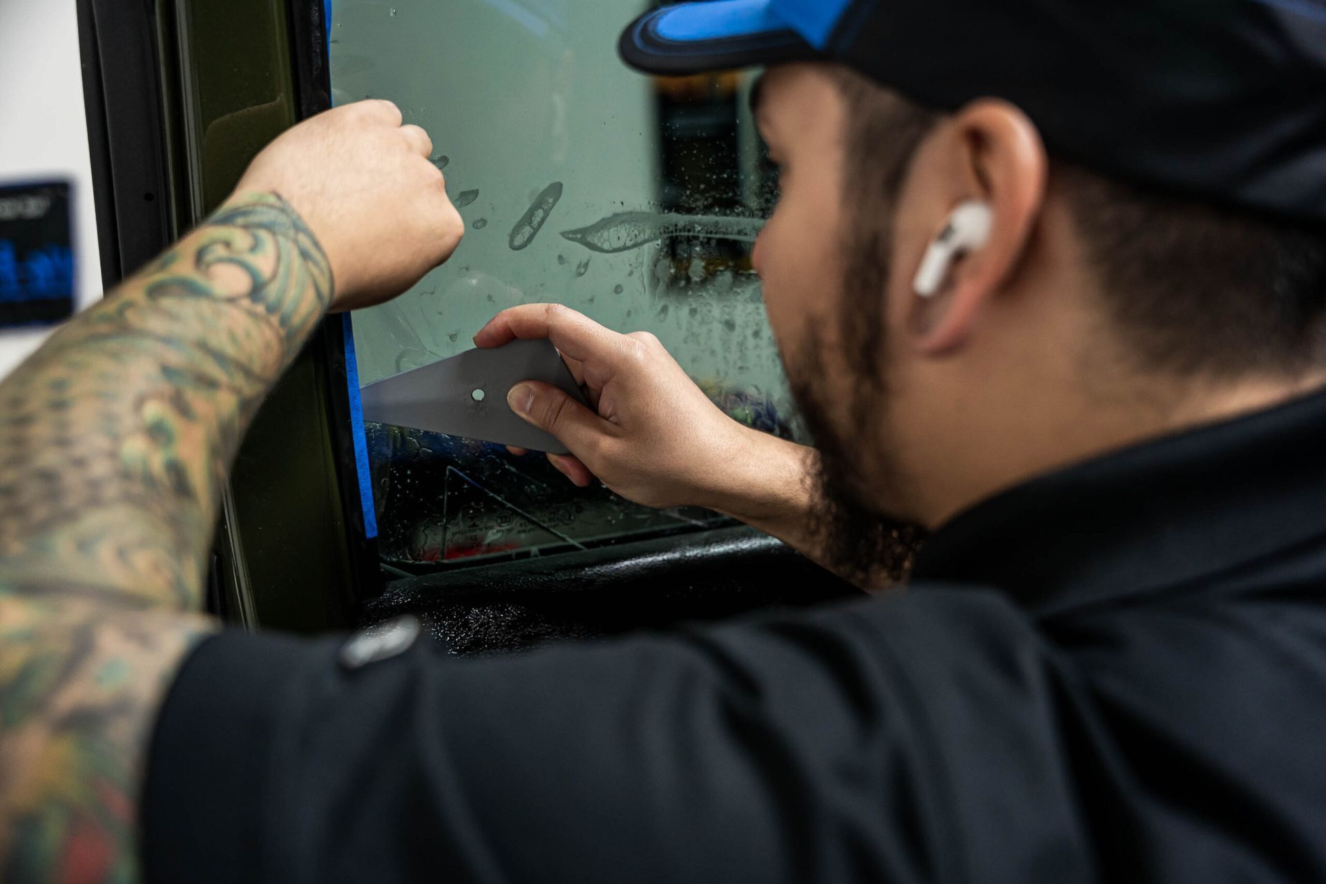 A man is applying window tinting to a car window.