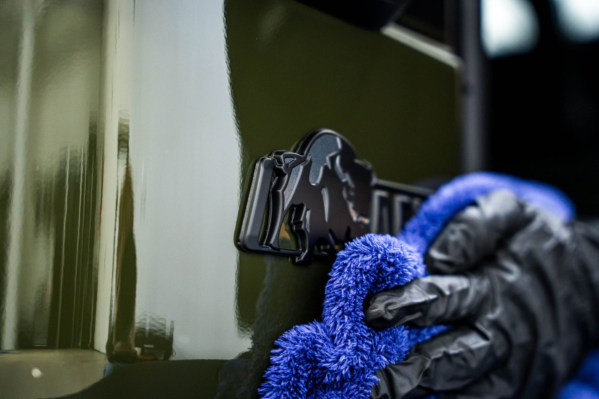 A person is cleaning a car with a blue towel.