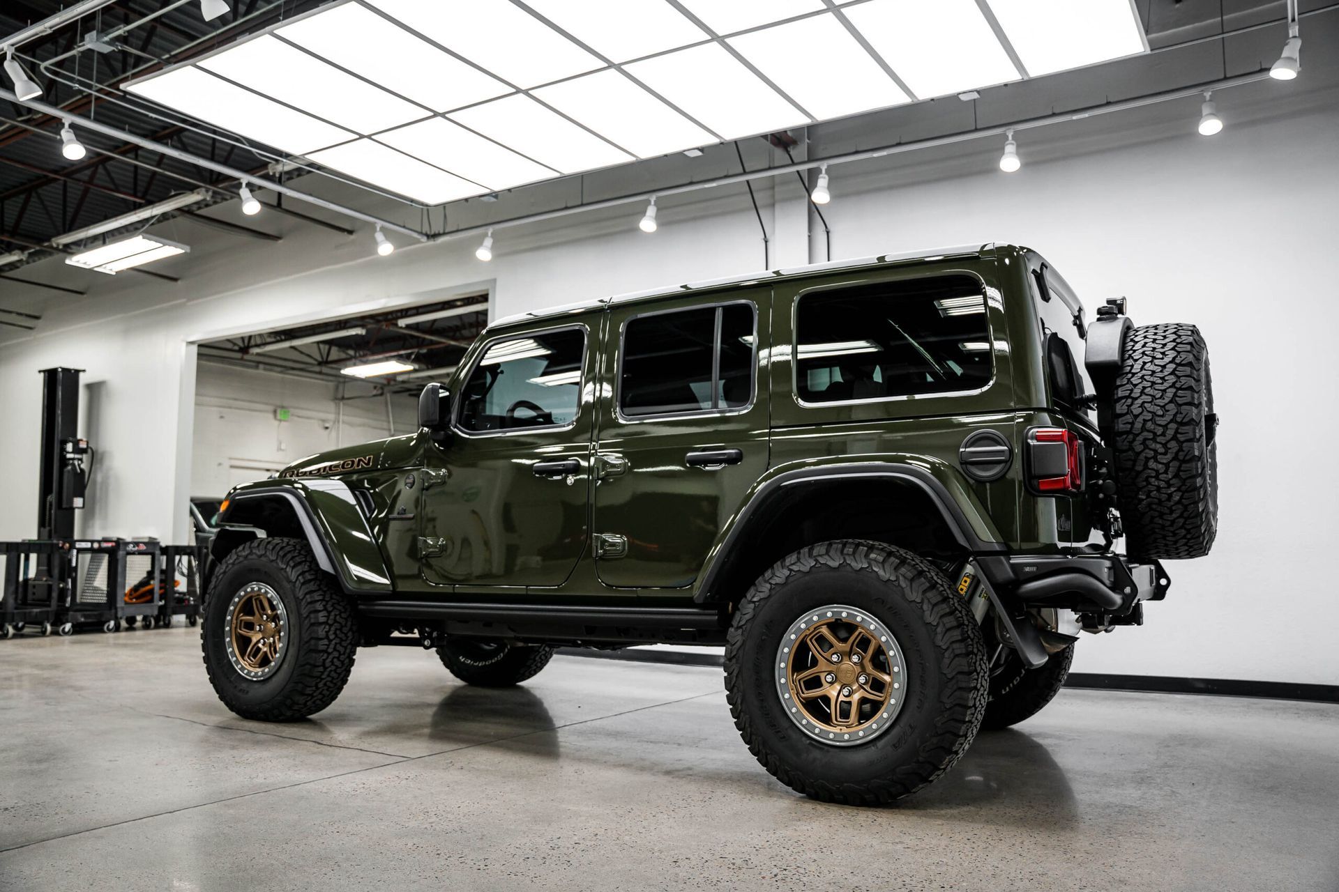 A green jeep wrangler is parked in a garage.