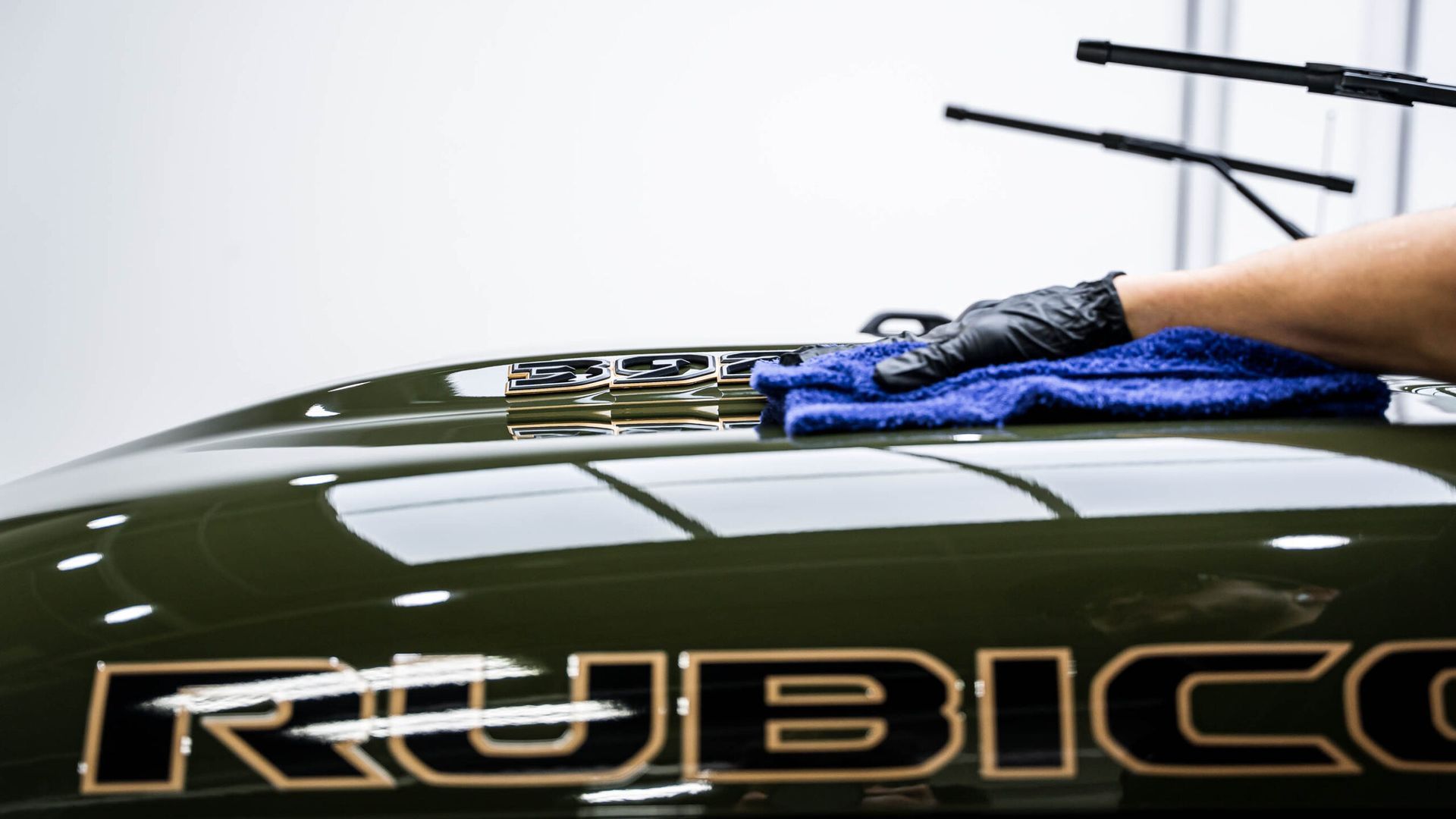 A person is cleaning the roof of a car with a towel.