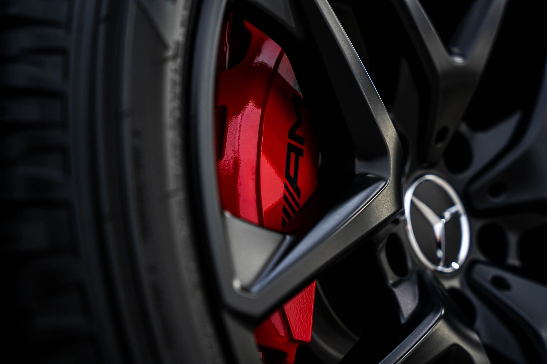 A close up of a mercedes wheel with a red brake caliper.