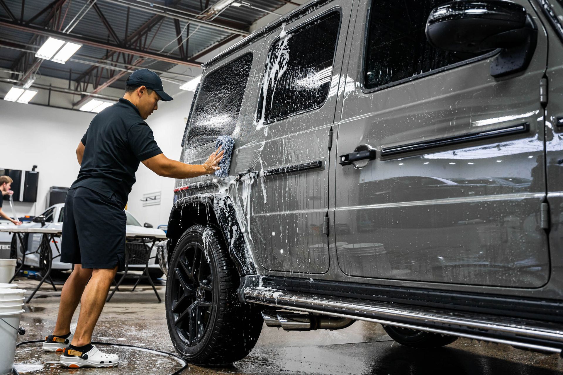 A man is washing a jeep in a garage.