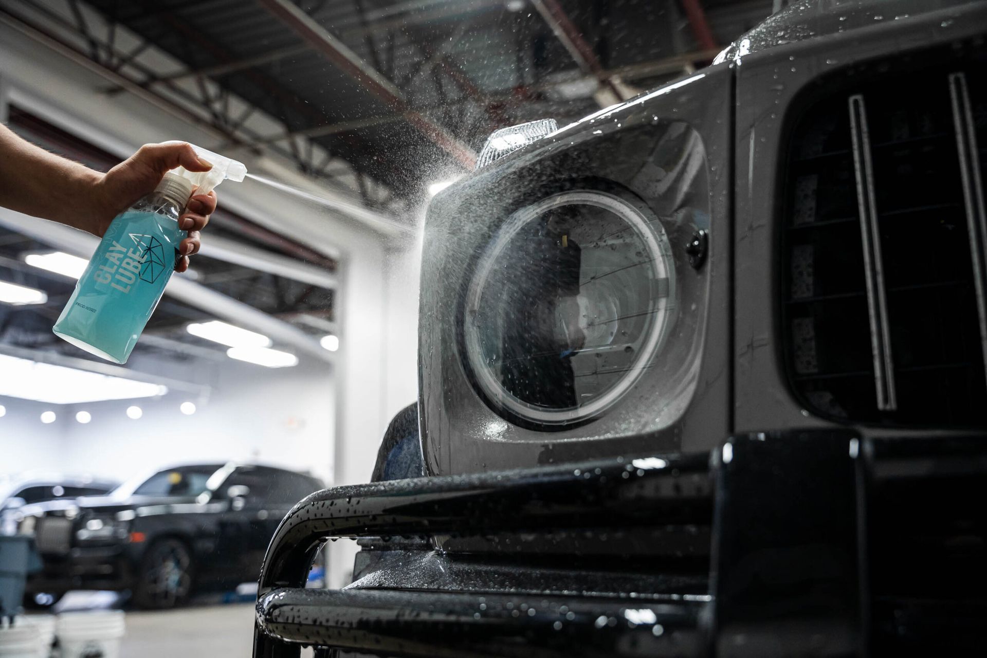 A person is spraying a car with a spray bottle in a garage.