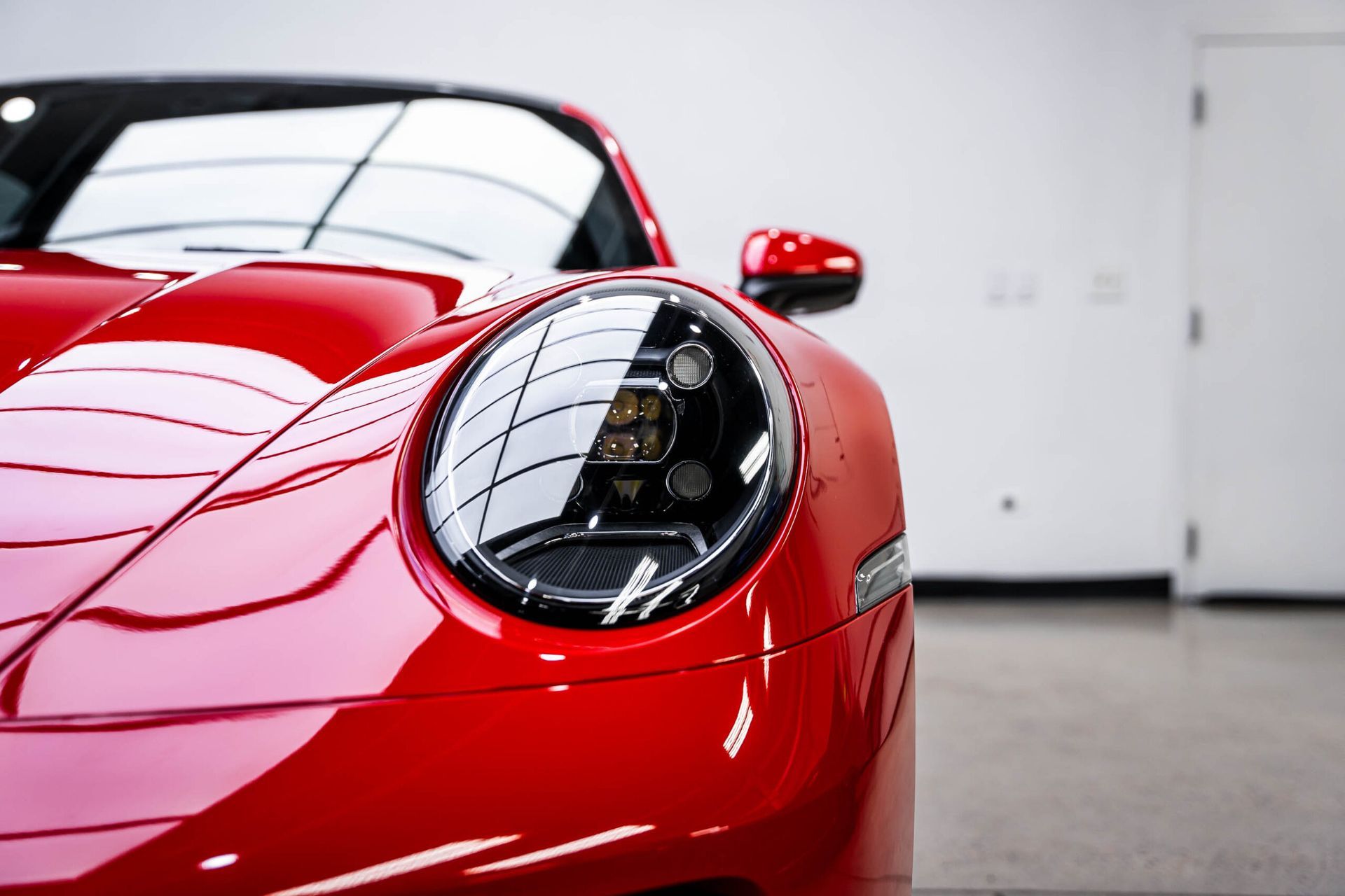 A close up of a red sports car 's headlight in a garage.