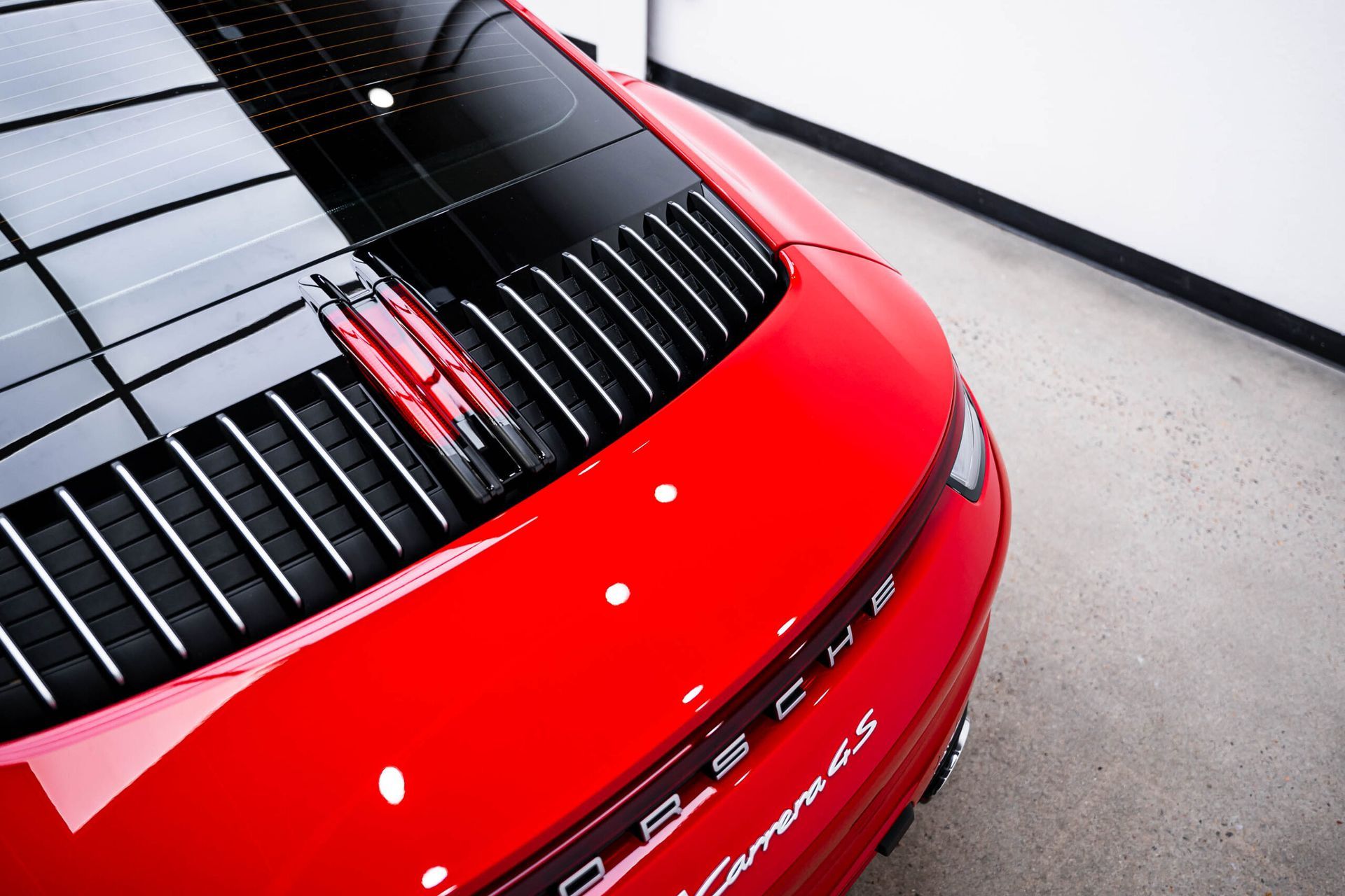 A red porsche car is parked in a garage