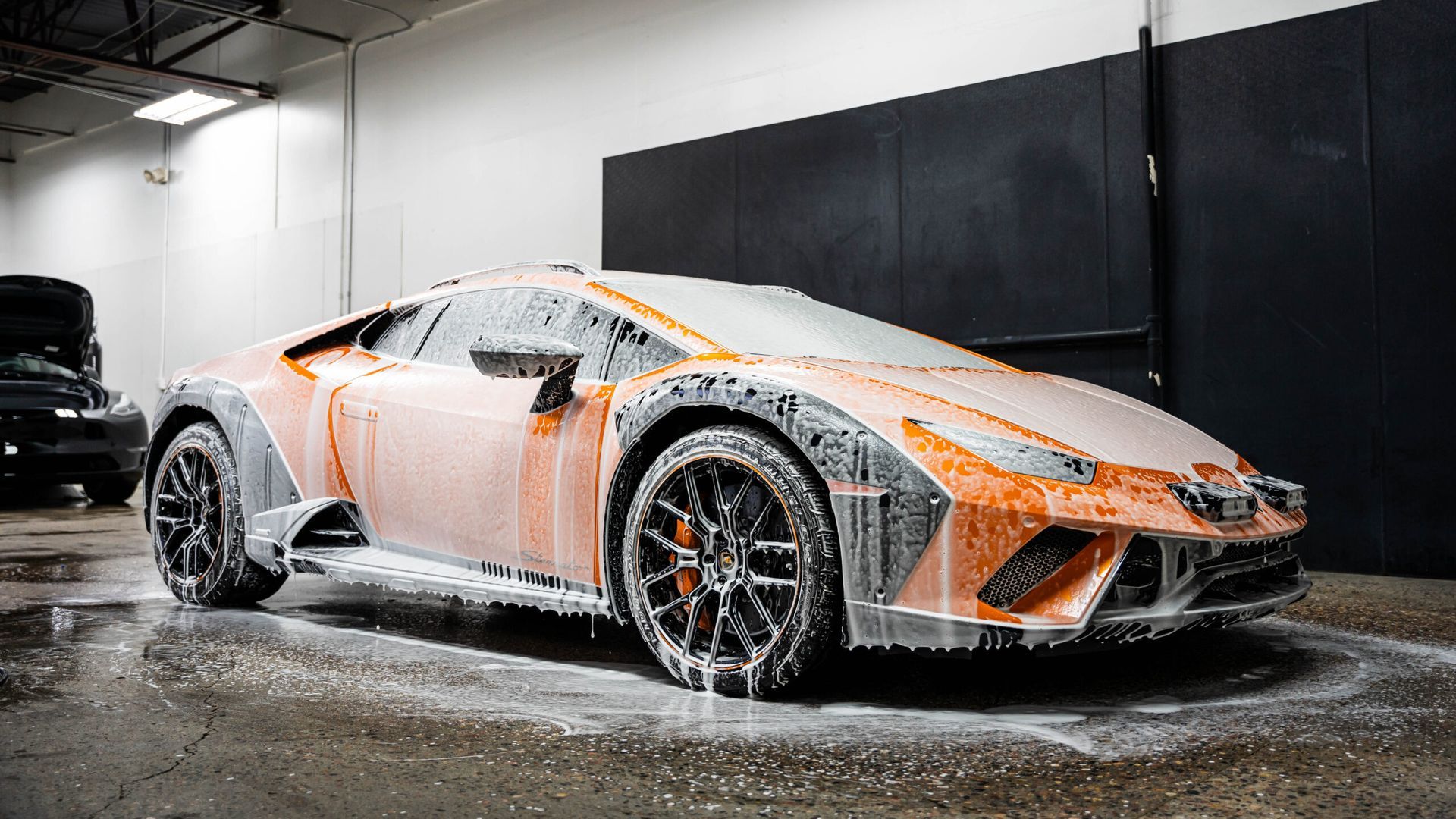 A lamborghini huracan is covered in foam in a garage.