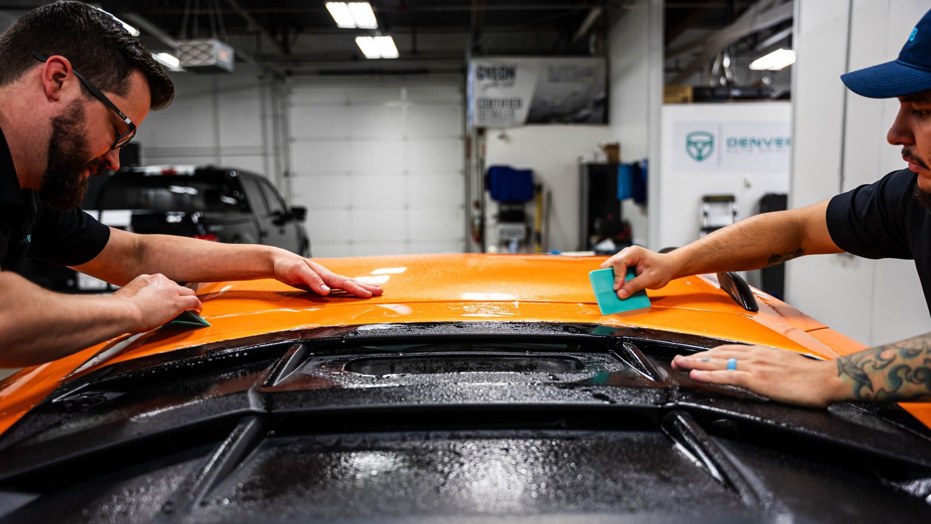 Two men are working on a car in a garage.