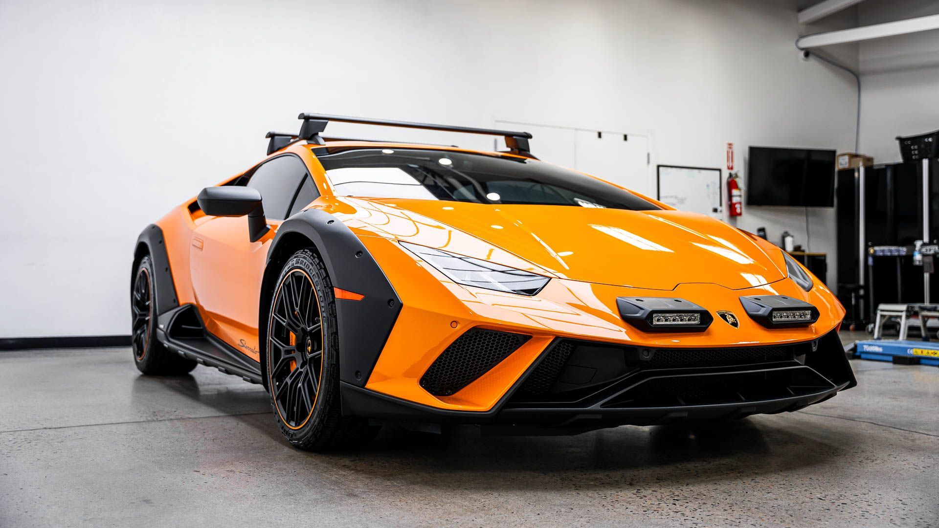 An orange lamborghini huracan is parked in a garage.