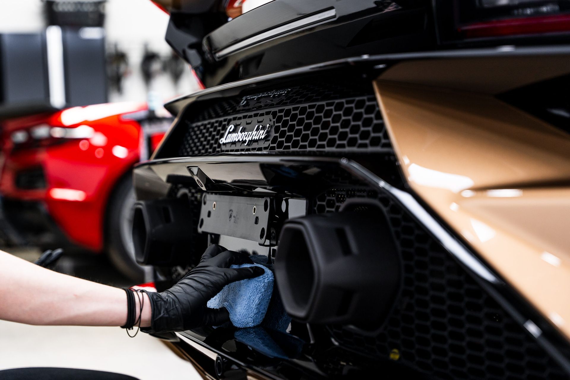 A person is cleaning the exhaust pipe of a sports car.