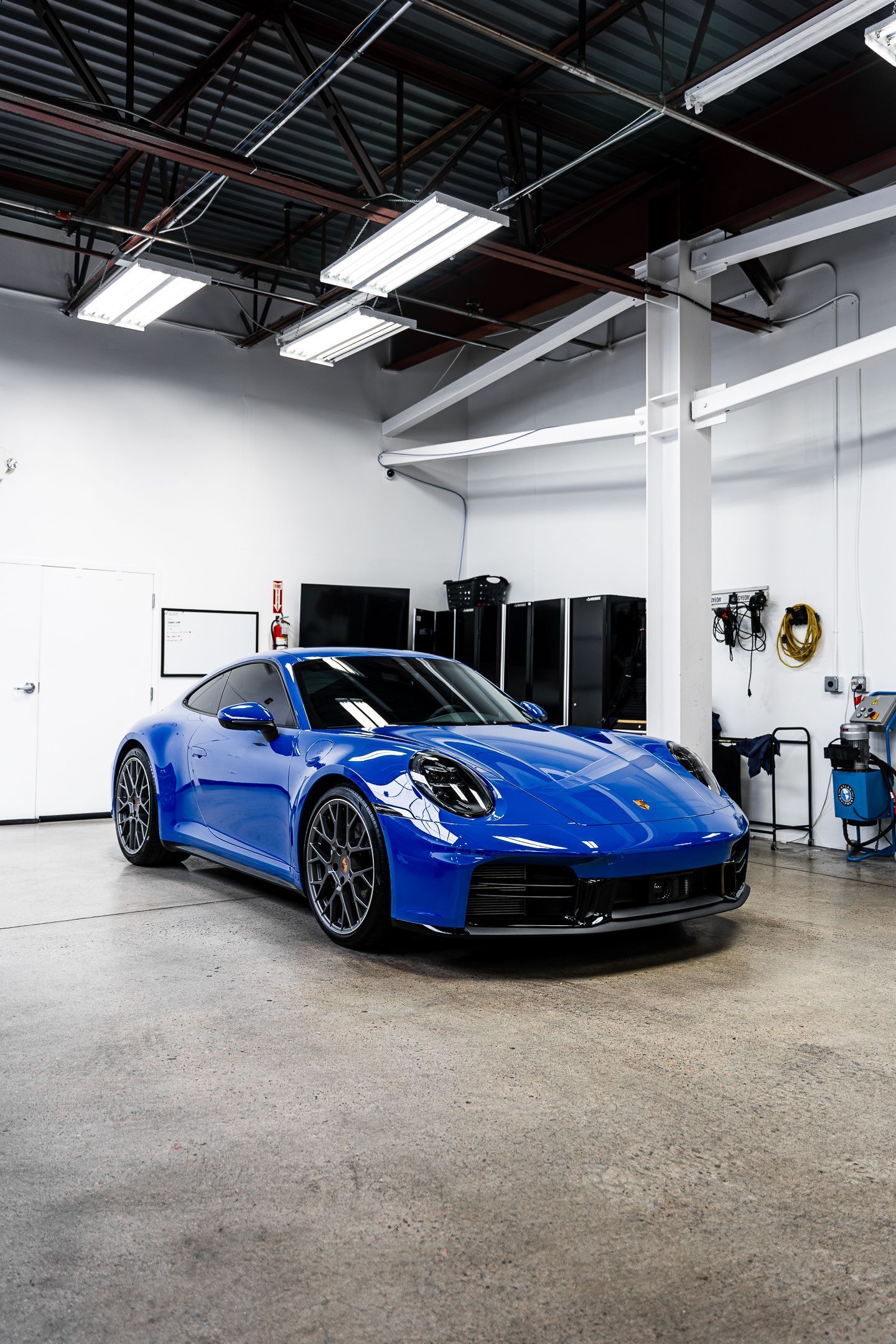 A blue porsche 911 is parked in a garage.