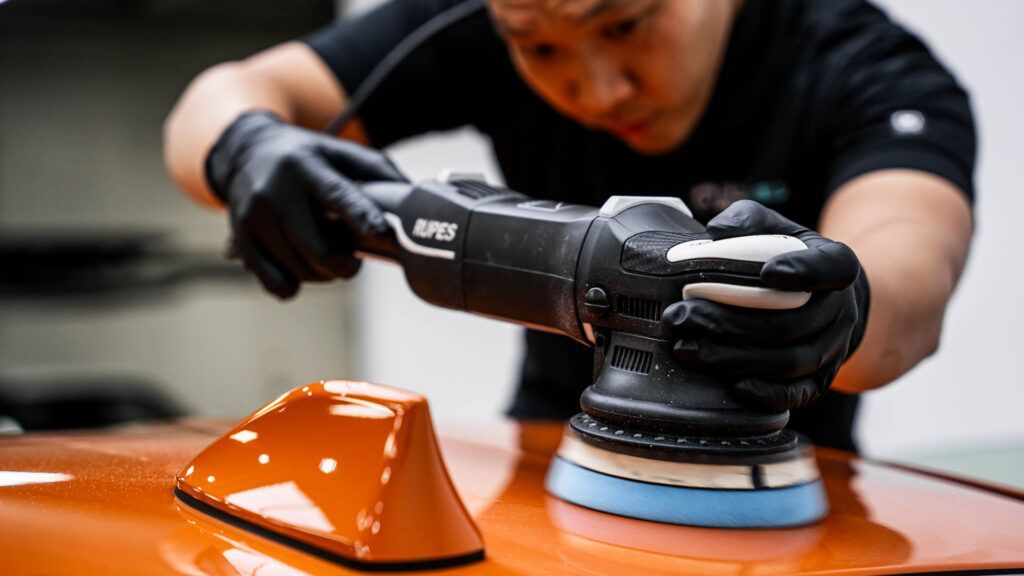 A man is polishing a car with a machine.