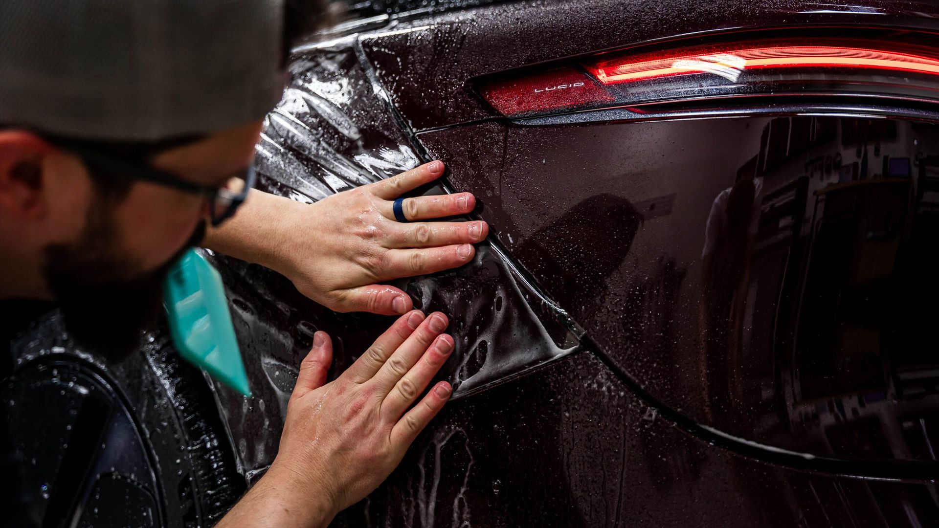 A man is wrapping a car with plastic wrap.