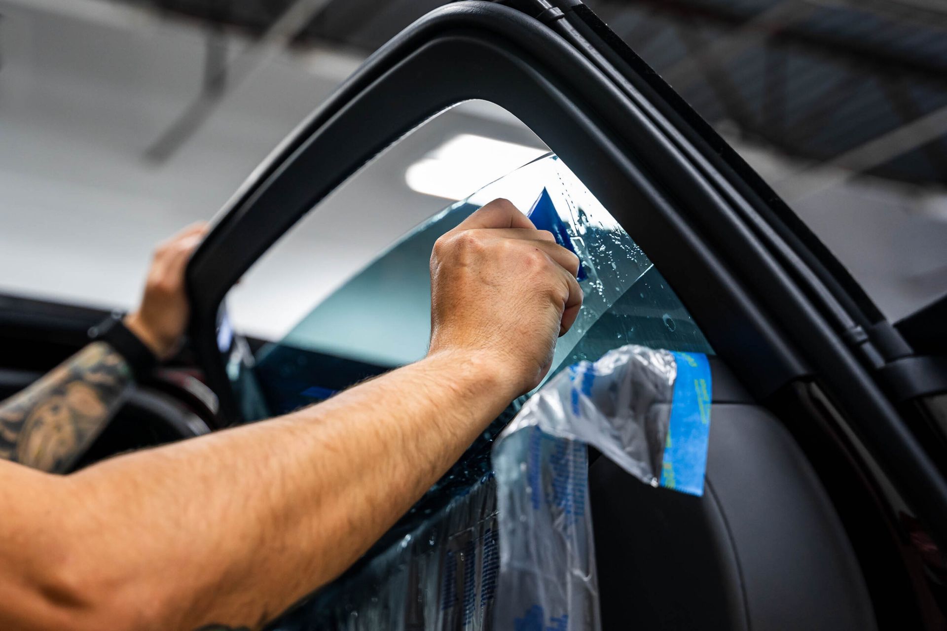 A man is applying window tinting to a car window.