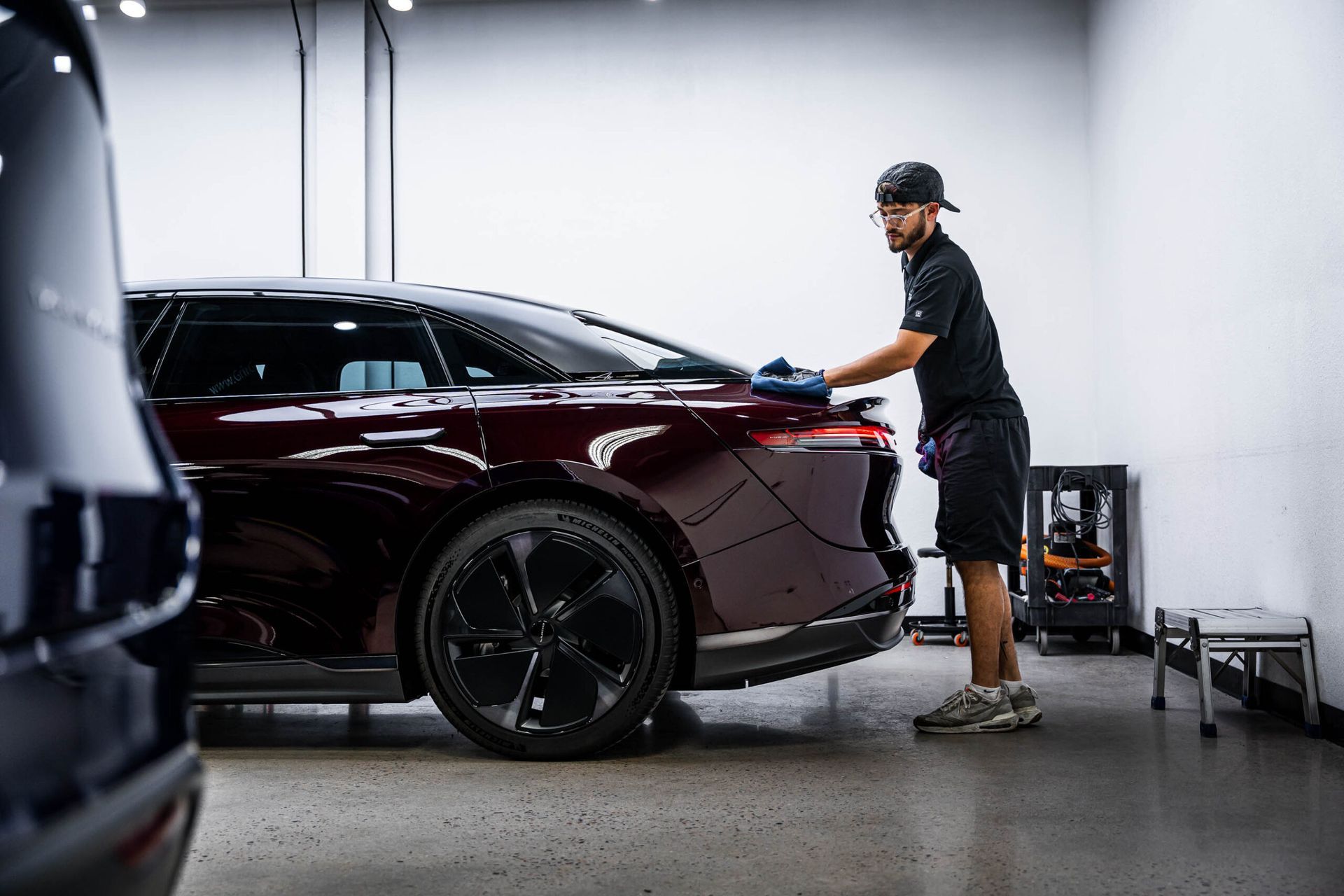 A man is polishing a car in a garage.