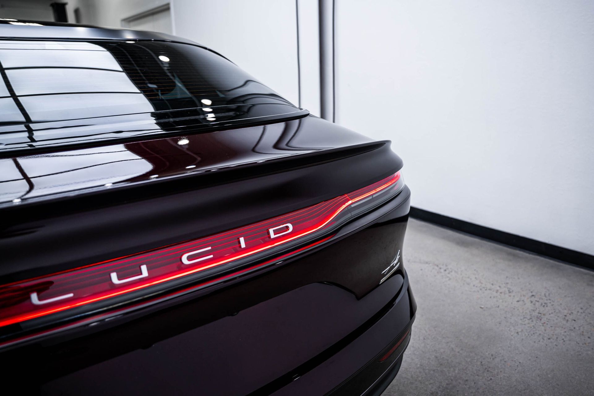 The rear end of a black lucid car is shown in a garage.