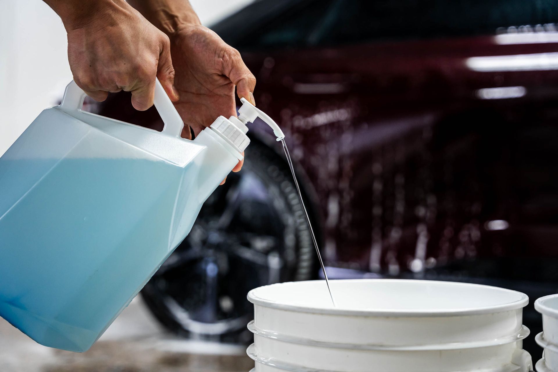 A person is pouring water from a bottle into a bucket.