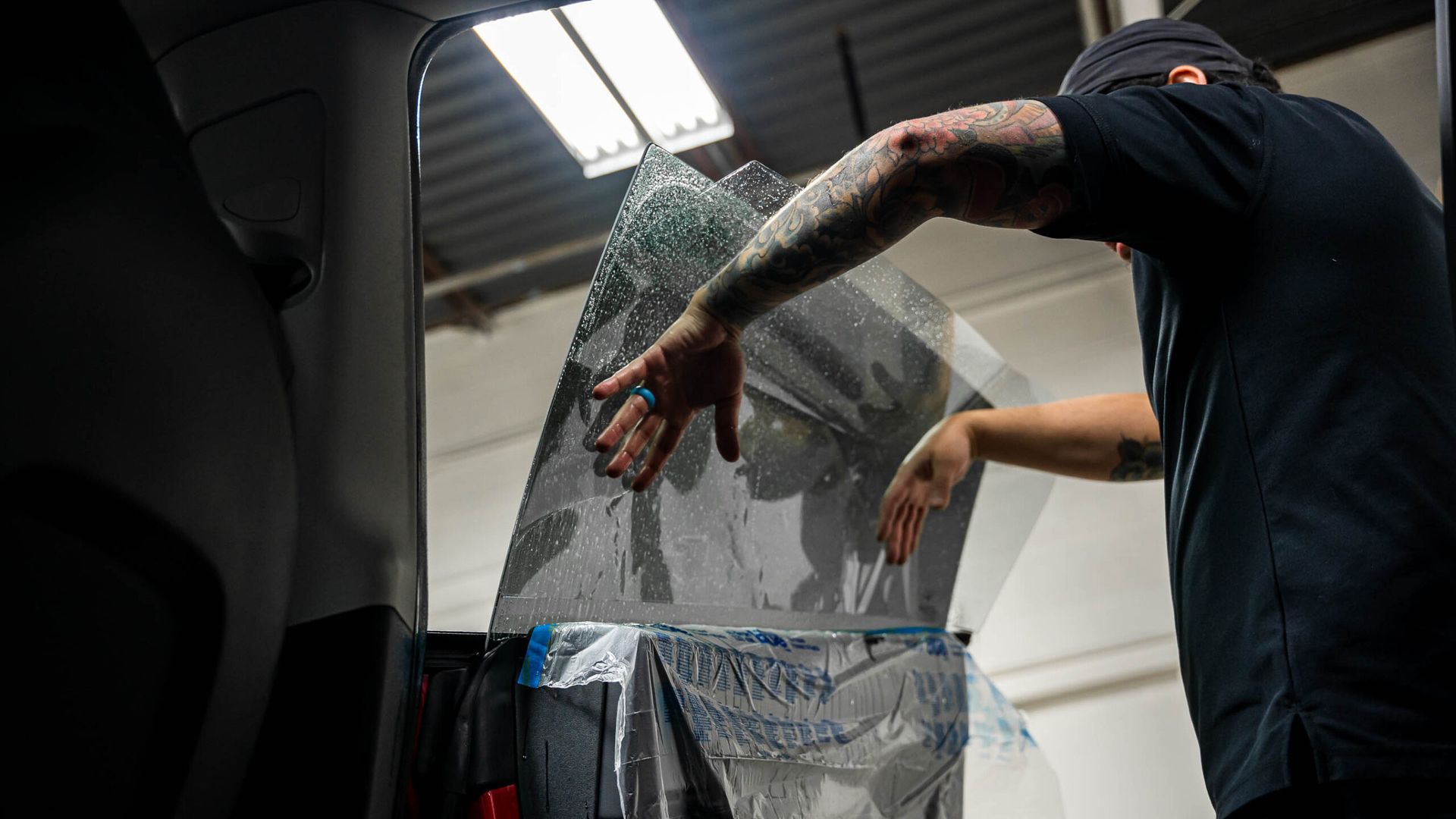 A man is applying tinted glass to a car window.